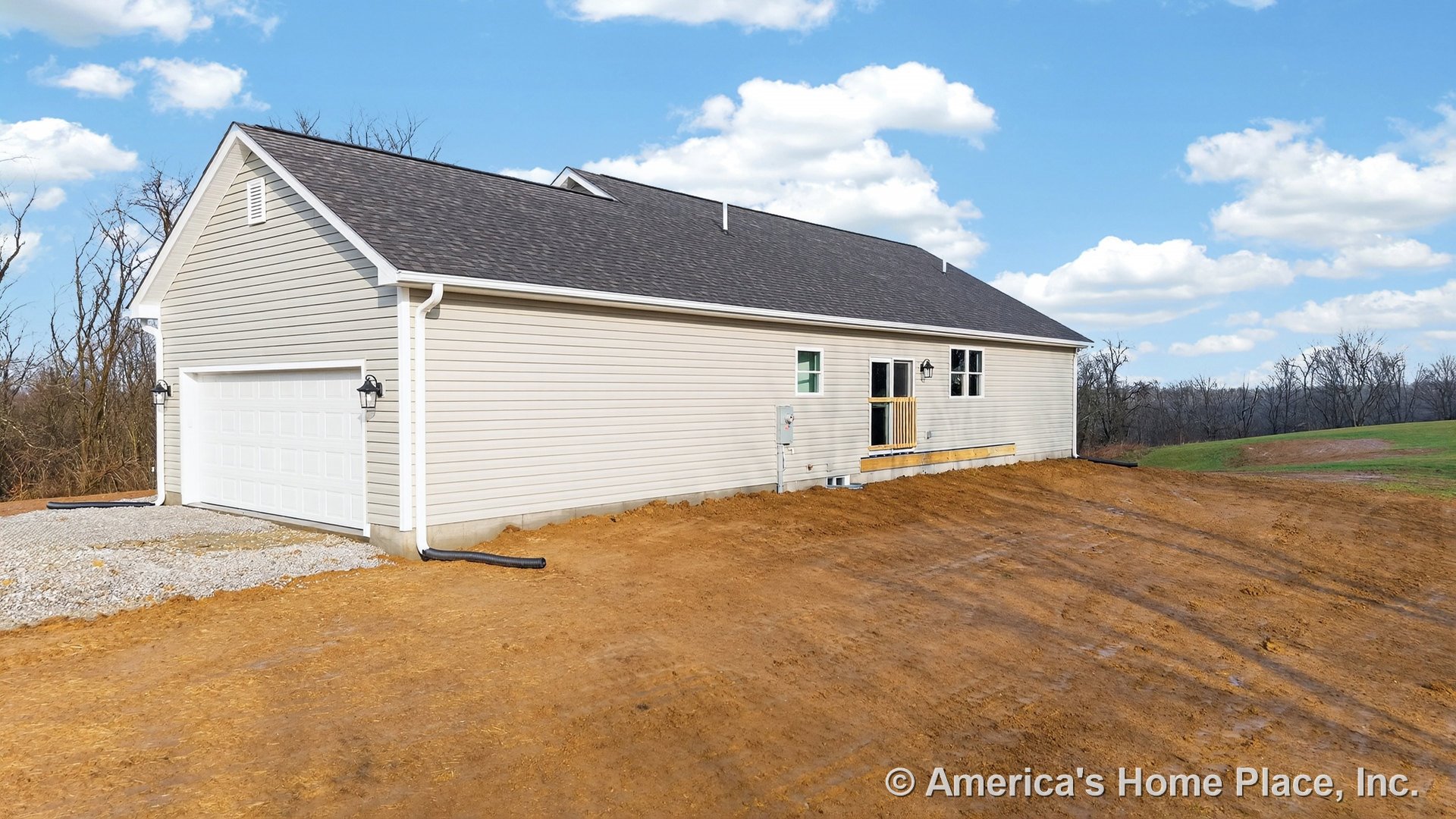 Beige vinyl siding exterior with attached two-car garage featuring a white door, unfinished rear porch, double-hung windows, wall-mounted exterior lighting, white trim, roof