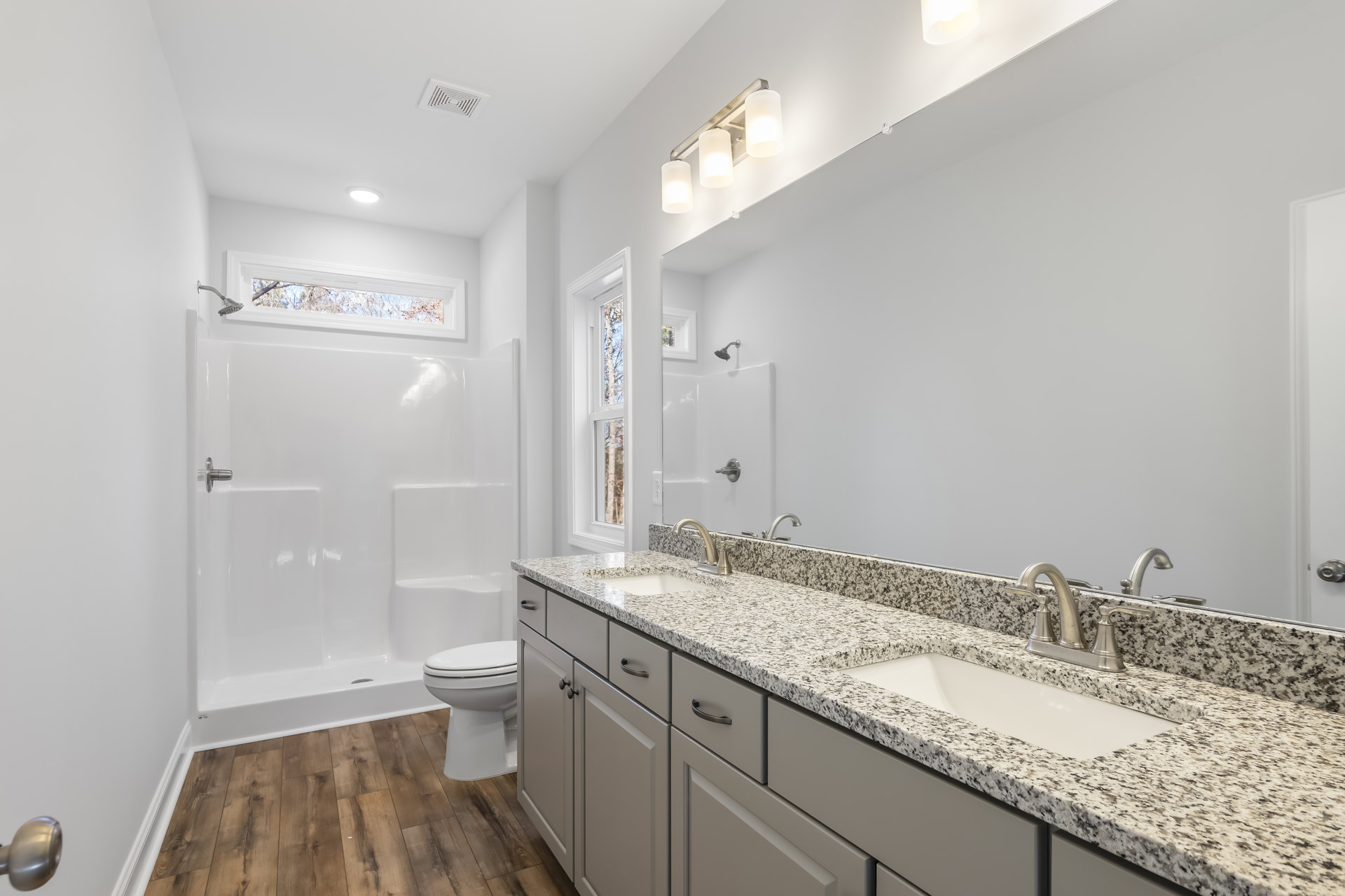 Modern bathroom featuring a white porcelain sink with chrome faucet, stone countertop, tiled walls, glass-enclosed shower, and white toilet with closed lid