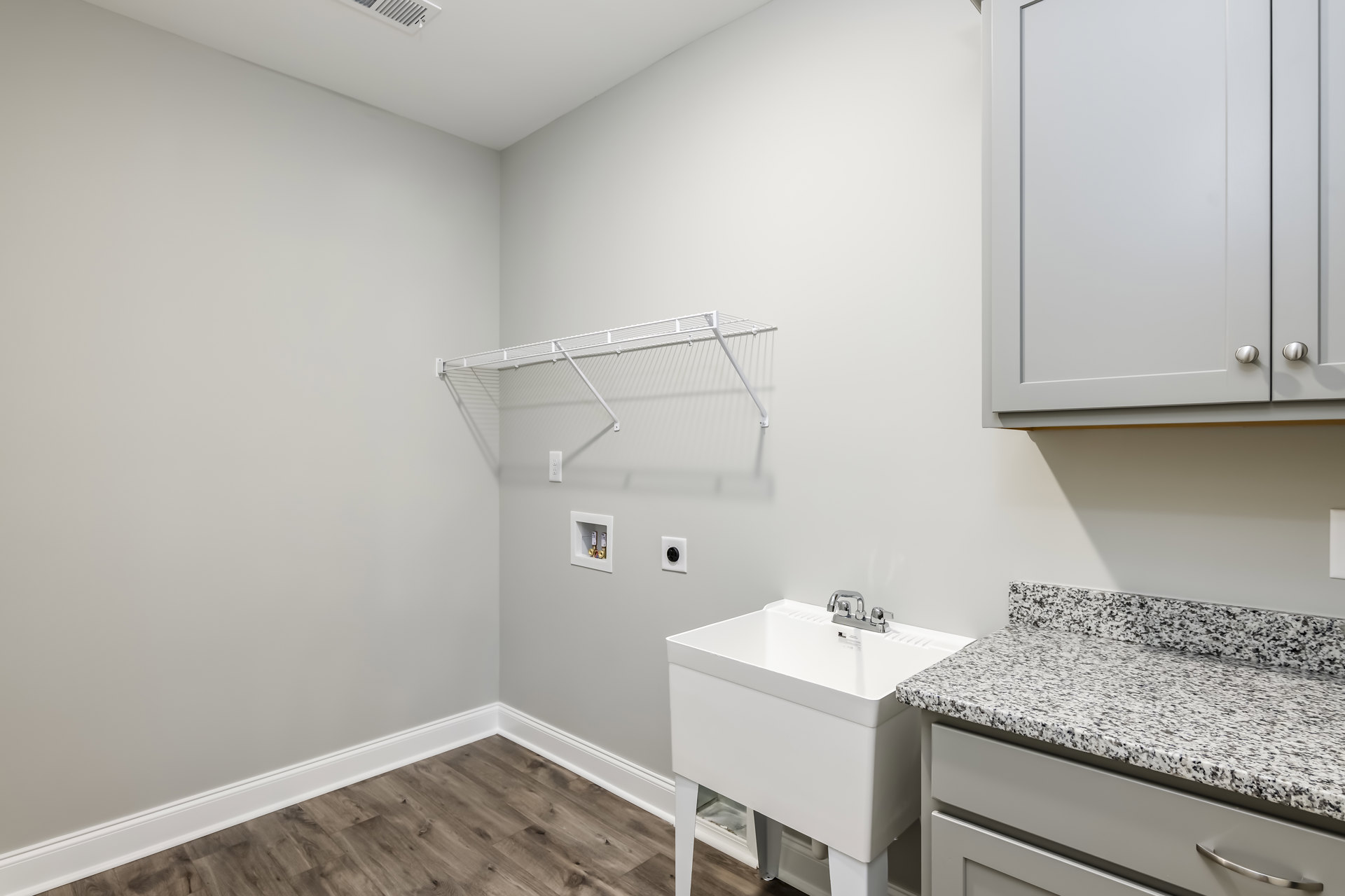 Modern bathroom with white rectangular sink, chrome faucet, floating wood shelf, light tile backsplash, and white cabinetry with silver handles