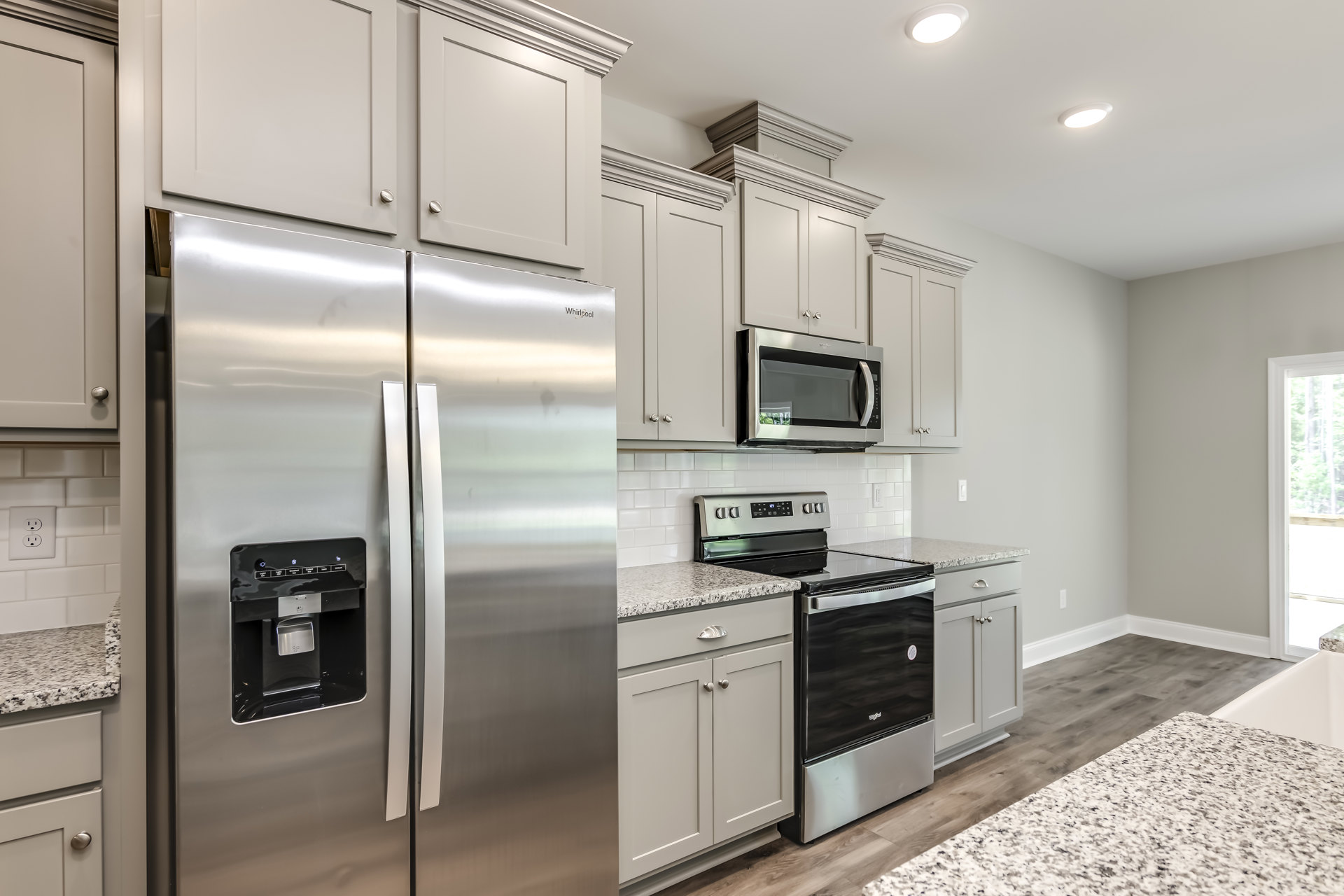 Kitchen with stainless steel refrigerator, built-in microwave above white cabinetry, black and silver oven, light countertops, and modern appliances
