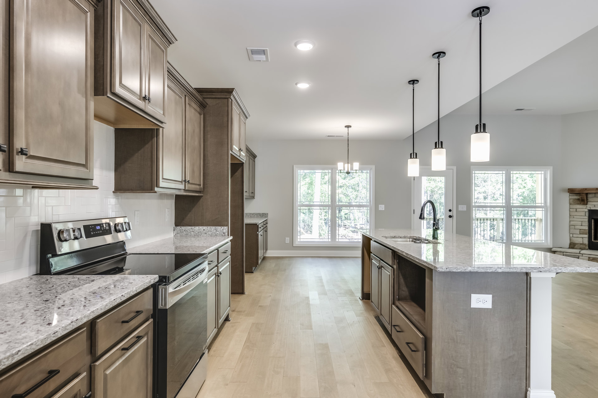 Kitchen with polished granite countertops, wood flooring, white cabinetry, stainless steel appliances, and a window above the sink.
