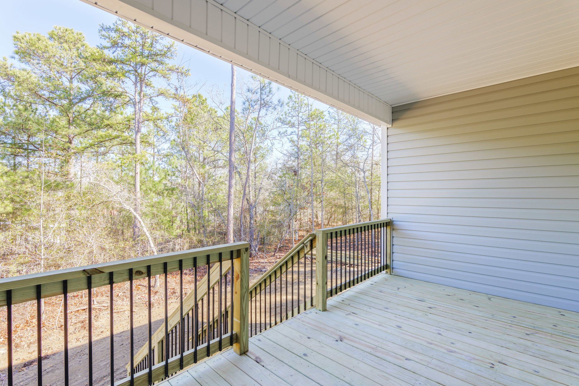 Wooden deck with metal railings overlooking leafy trees in the background