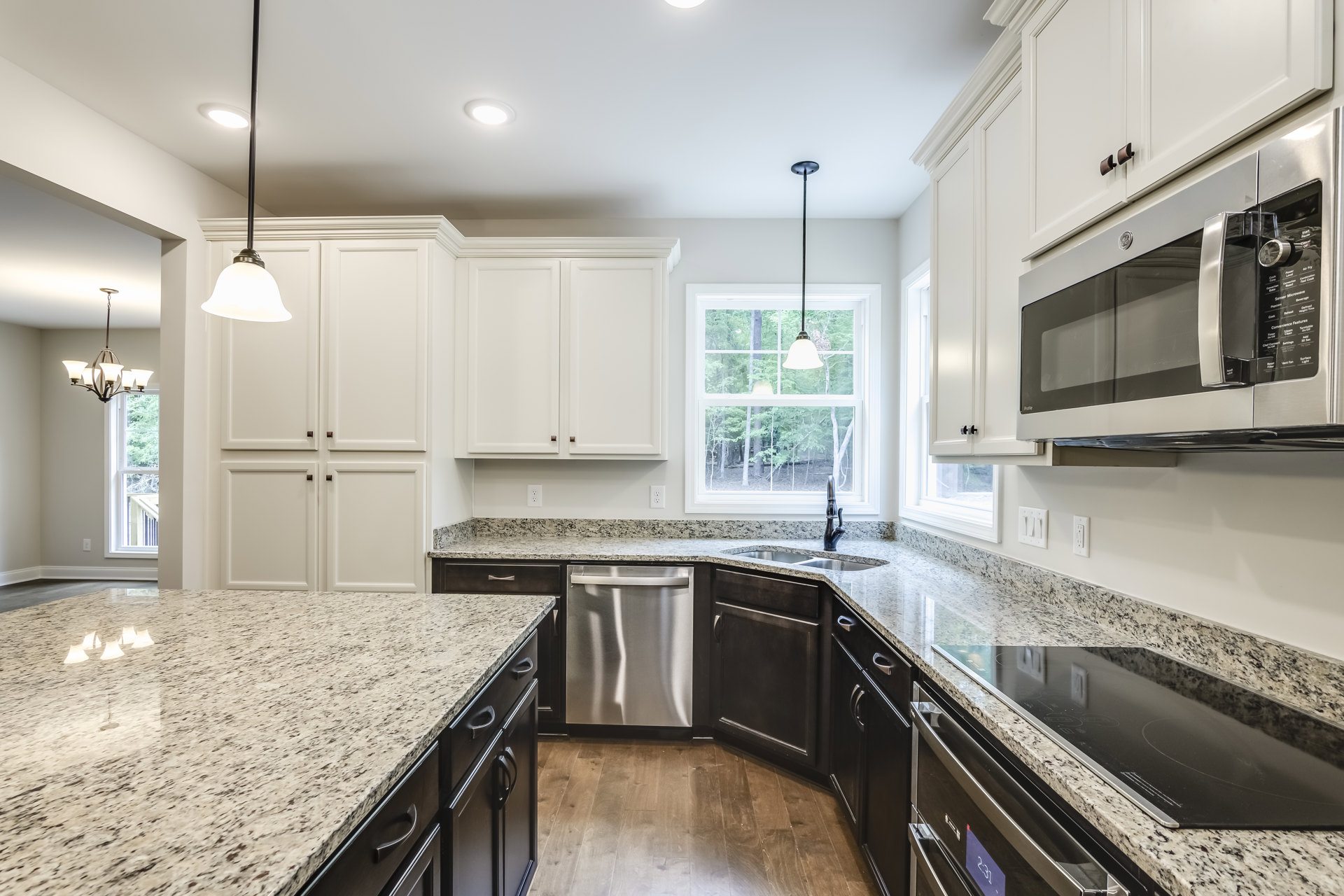 Granite countertop kitchen with stainless steel appliances, white cabinetry, undermount sink, and large window providing natural light