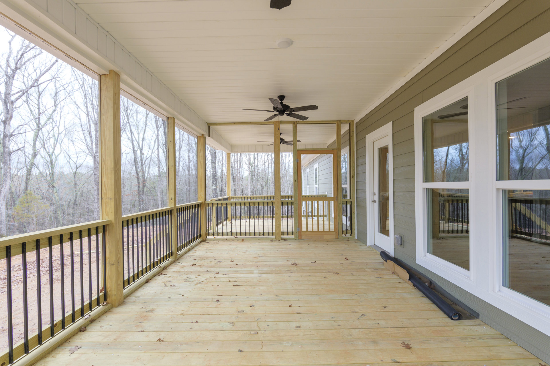 Wood deck with metal railings, white ceiling featuring two ceiling fans with wood blades, large windows along exterior wall
