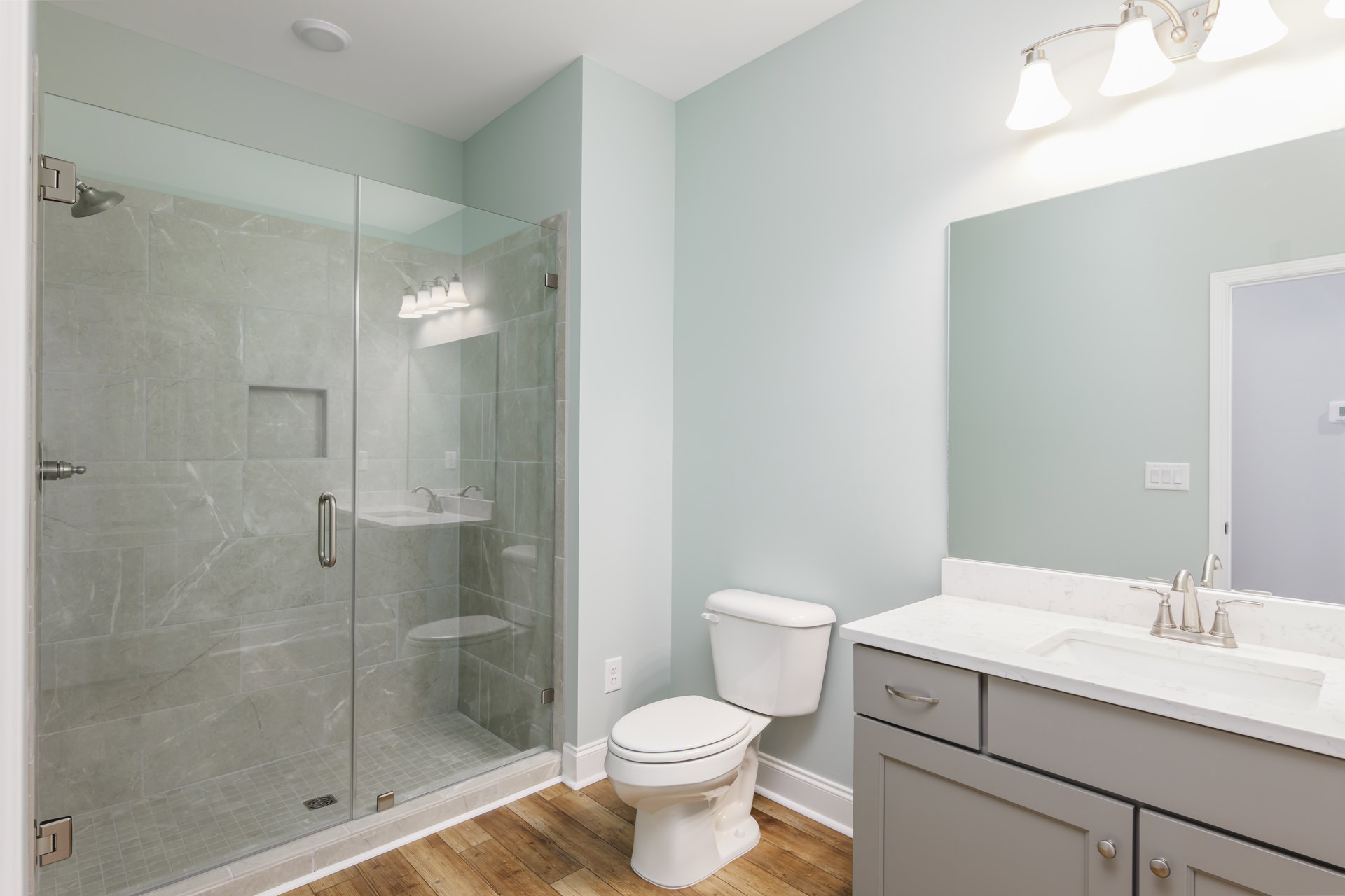 Bathroom with glass shower enclosure, white toilet with closed seat, tiled walls, chrome fixtures, and modern sink