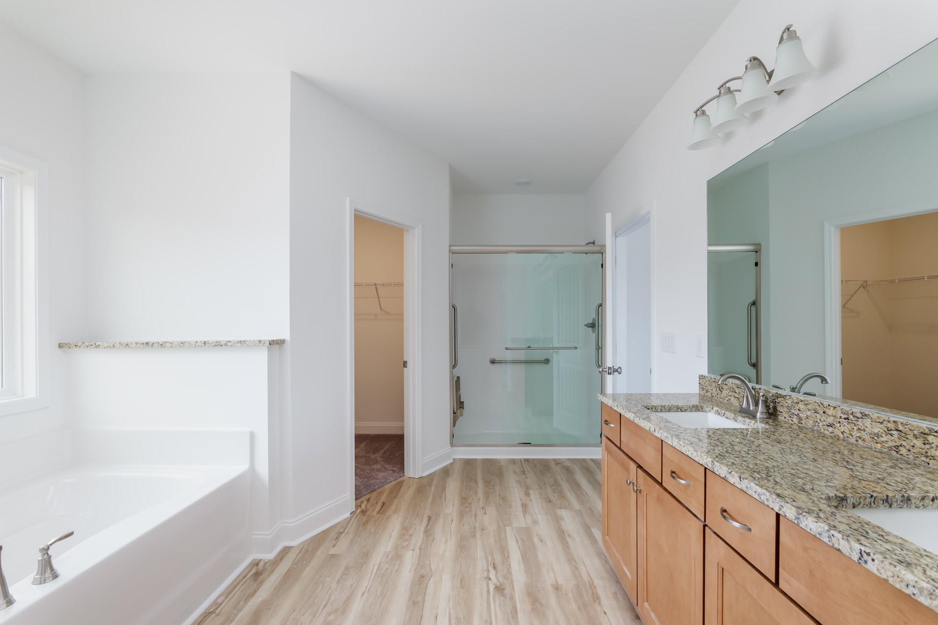 Bathroom featuring a frameless glass shower door with metal handle, granite countertop vanity, tile flooring, and modern light fixture above sink.