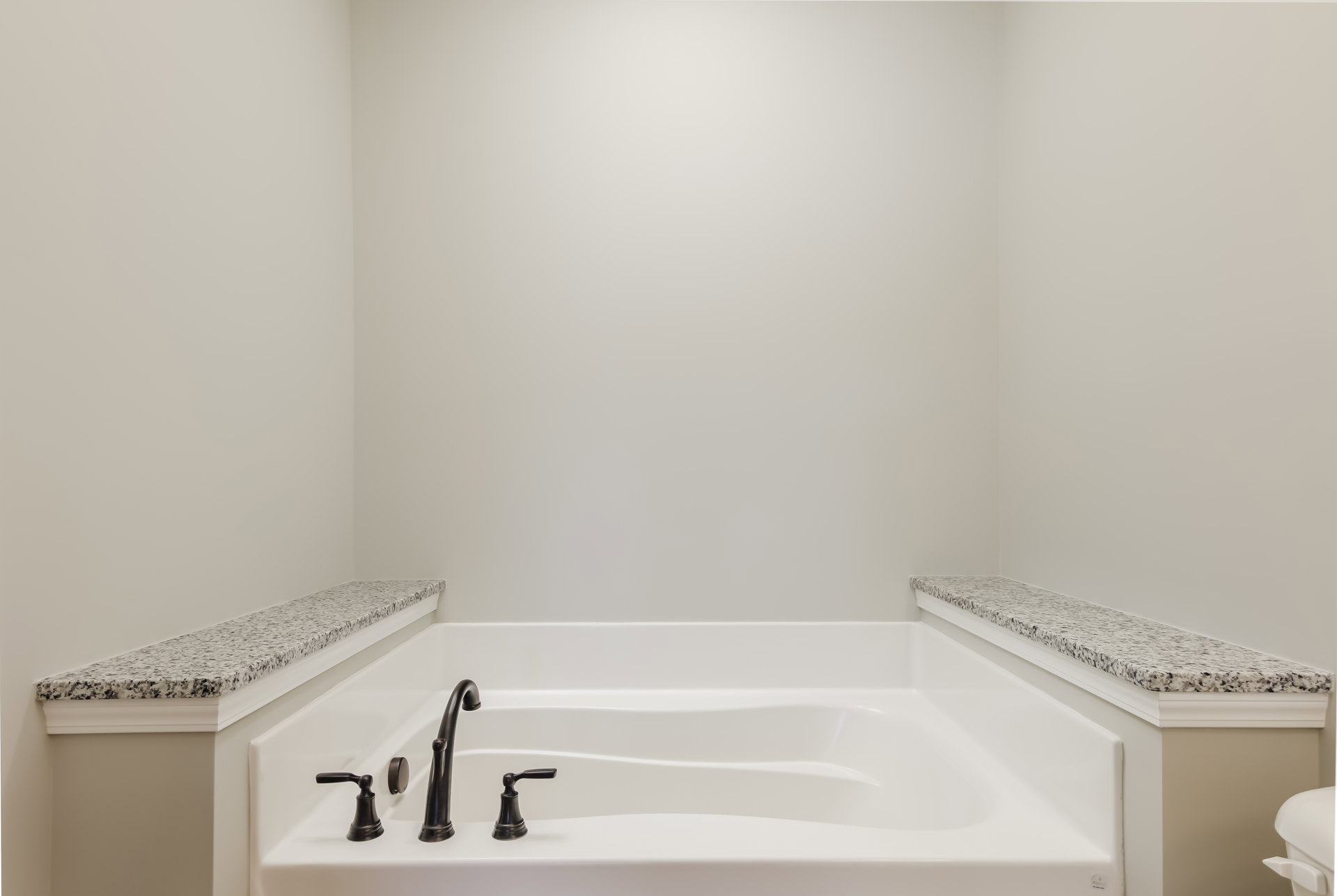 Freestanding white bathtub with matte black faucet set against light tile wall in modern bathroom