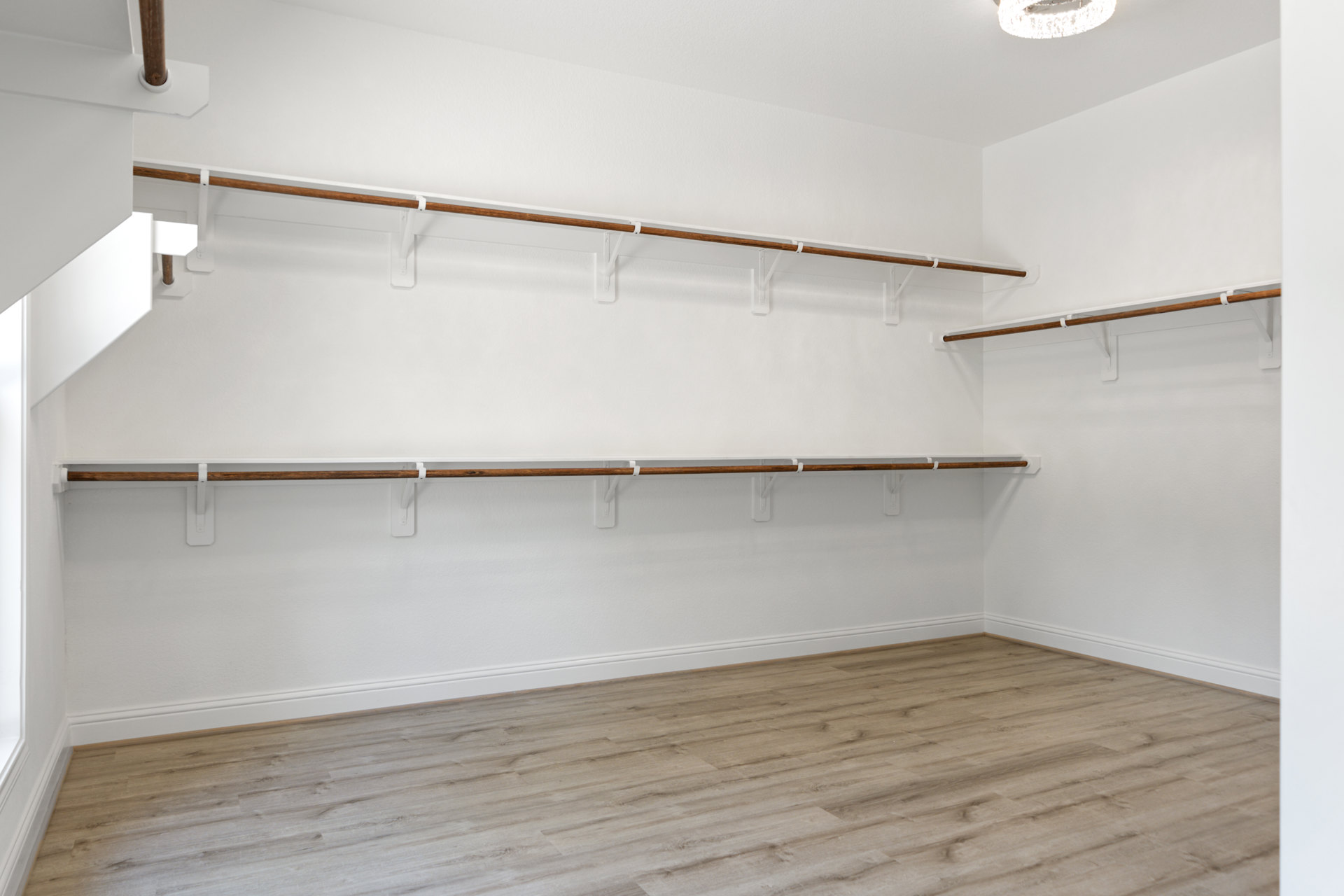 Empty closet with built-in white shelves, patterned wood floor, and white baseboards