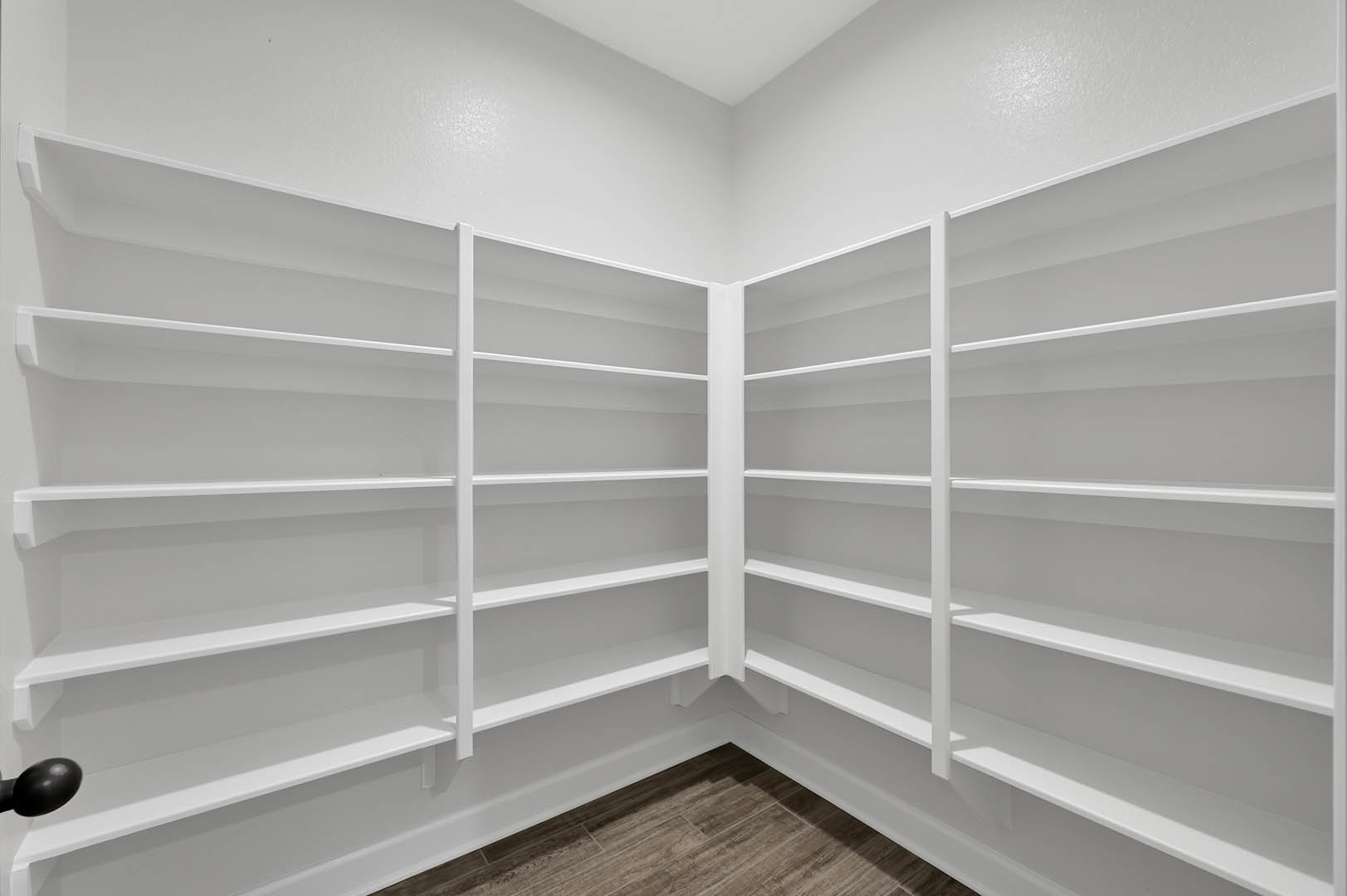 White built-in shelving unit against plaster wall, wood flooring, empty shelves, minimalist interior design