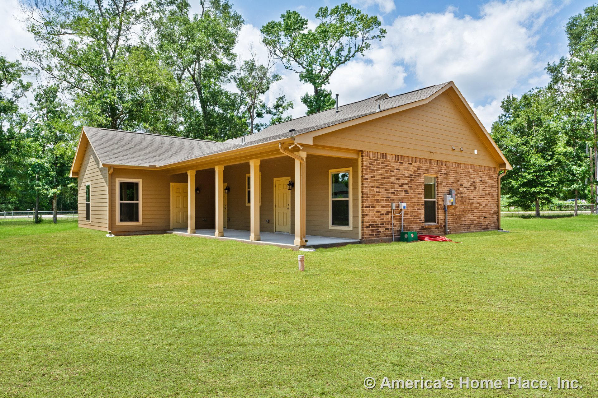 Covered porch supported by four columns, brick and siding exterior, multiple exterior doors, double-hung windows, sloped shingle roof, outdoor lighting fixtures, landscaped yard