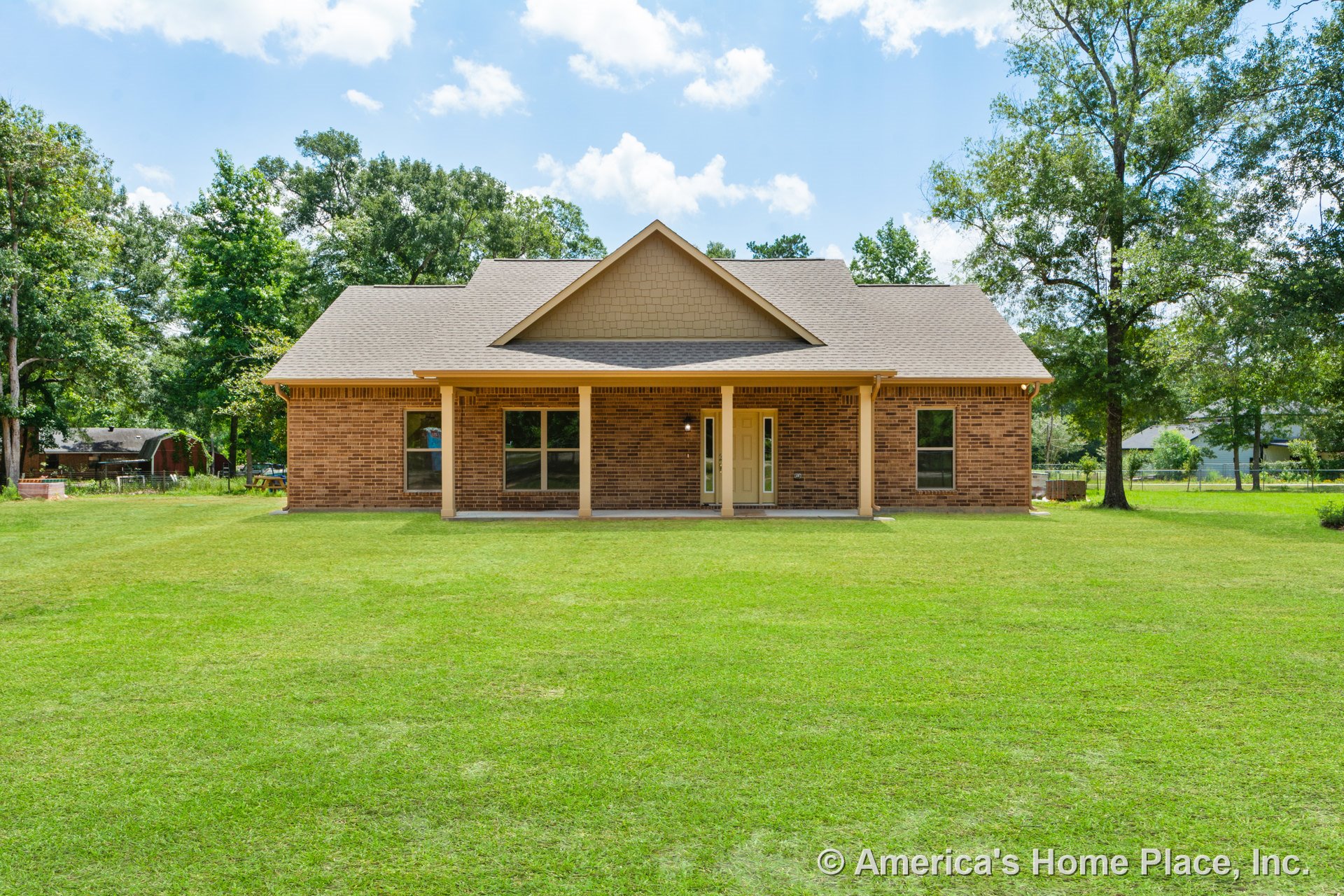 Brick exterior single-story home with covered front porch, double front doors, multiple large windows, gable roof, decorative trim, and outdoor lighting fixtures.