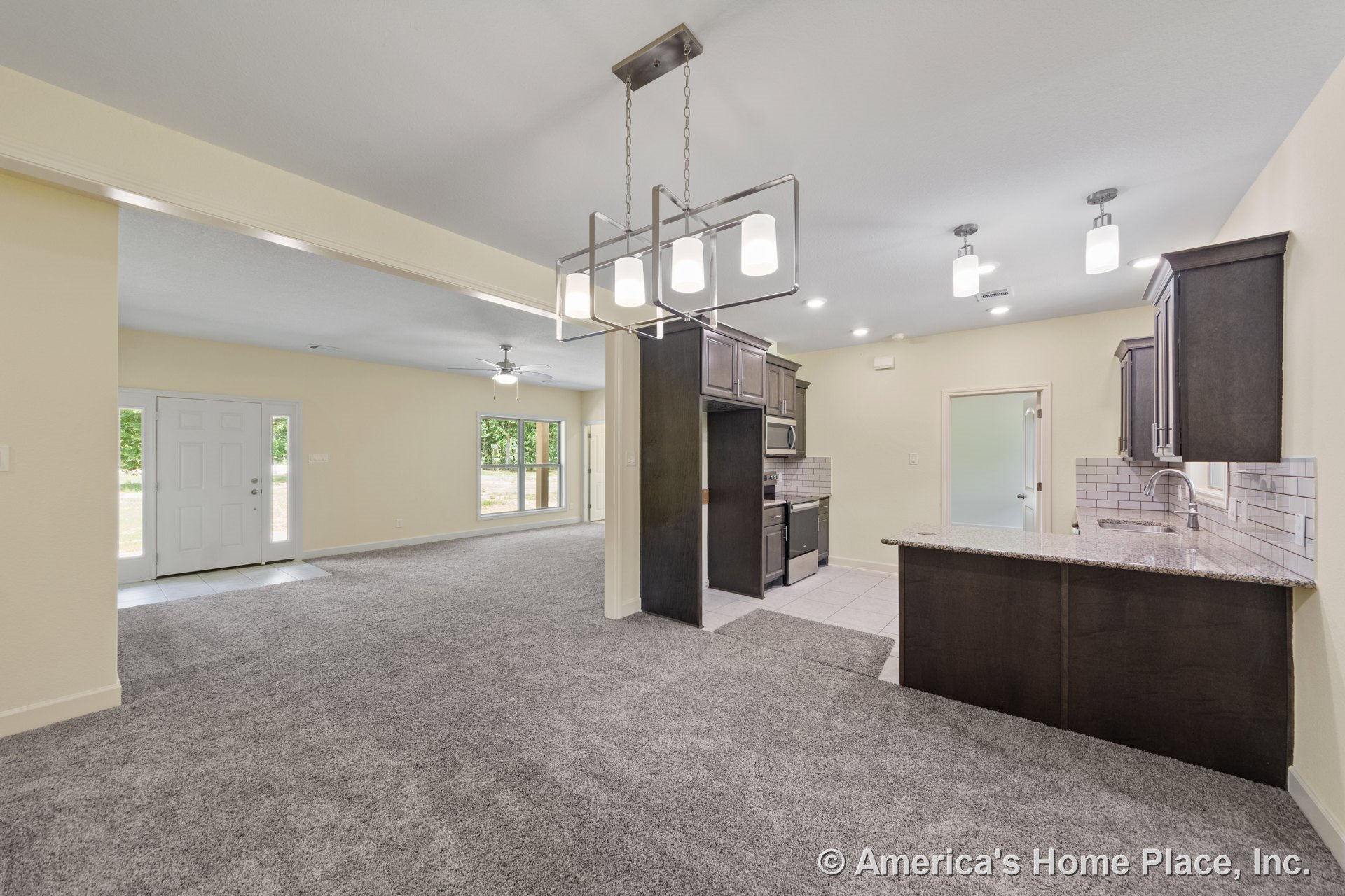 Open concept living area with kitchen featuring dark wood cabinets, granite countertops, subway tile backsplash, stainless steel appliances, modern pendant lighting, tile flooring