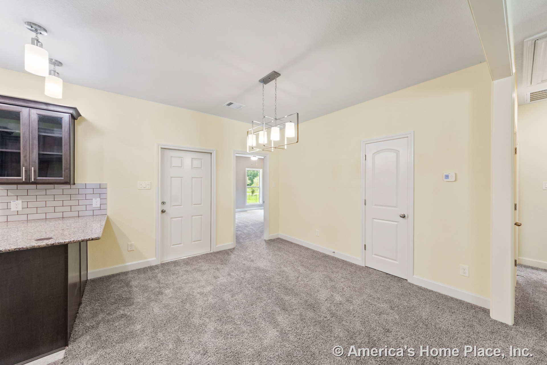 Carpeted dining area with rectangular ceiling light fixture, white paneled interior doors, open access to kitchen featuring granite countertops, dark wood cabinetry, and white