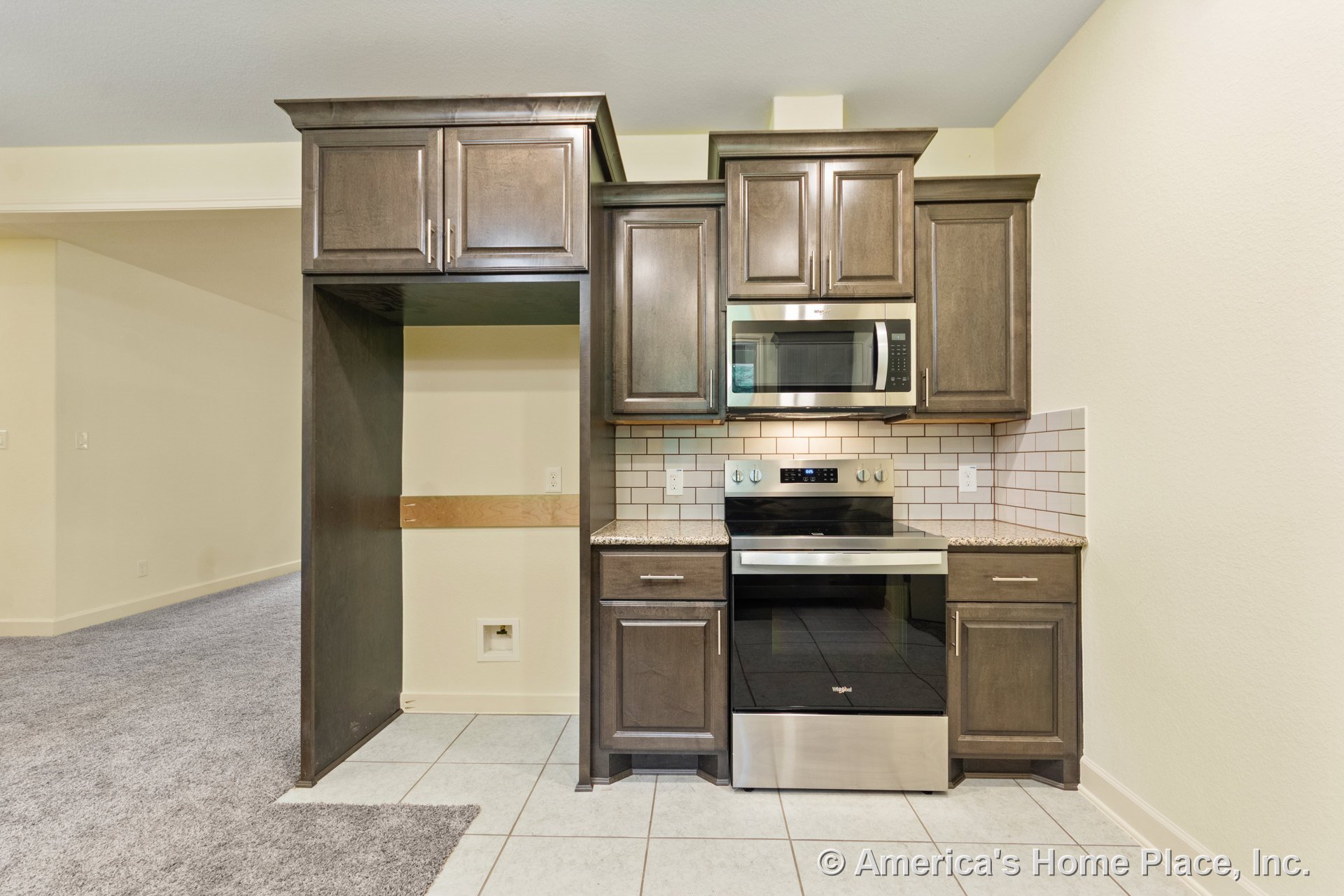 Dark wood upper cabinets and granite countertops with a stainless steel stove and built-in microwave, white subway tile backsplash, and tile flooring.