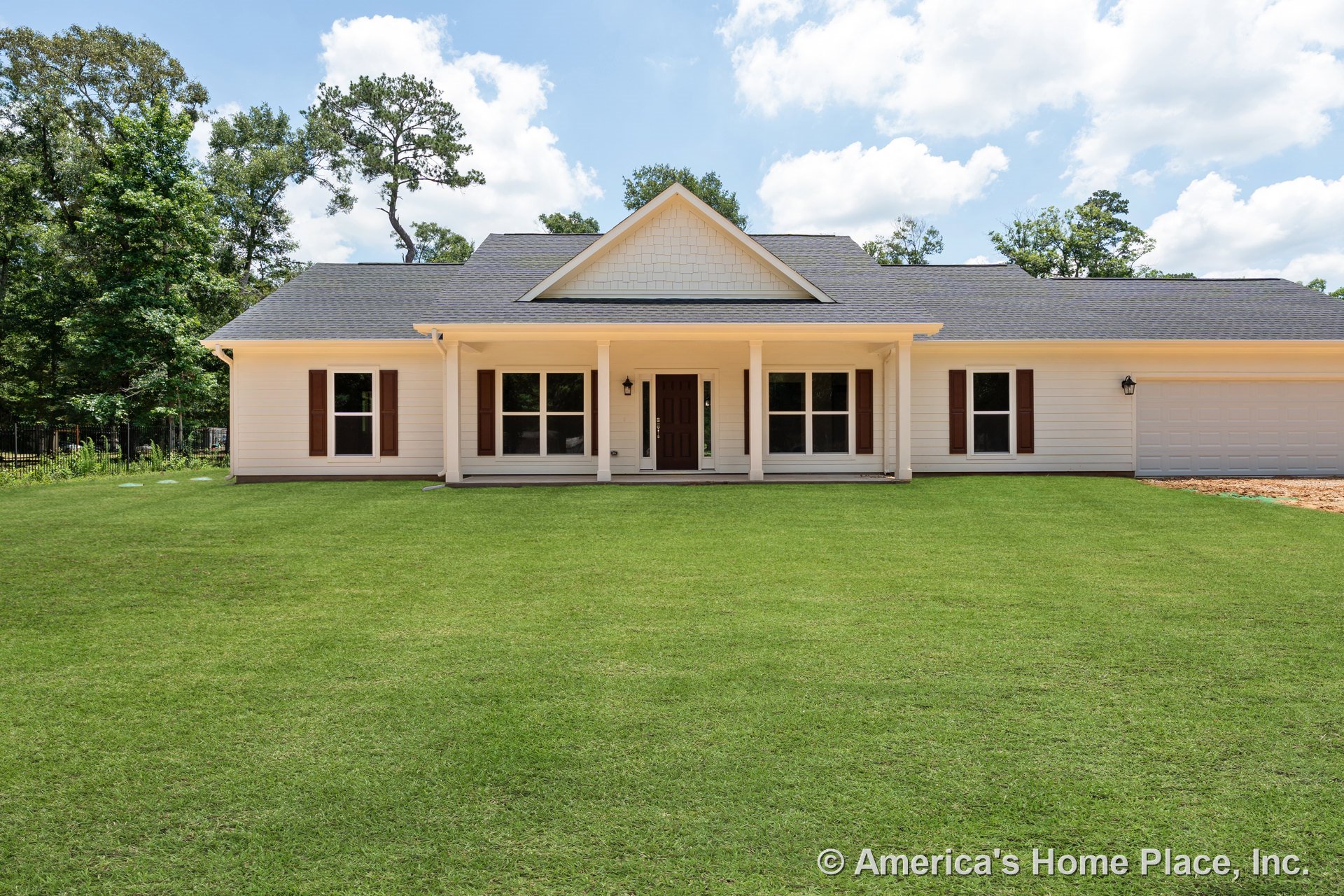 Covered front porch with four columns and gabled roof, white siding exterior, brown window shutters, dark front door, attached two-car garage, large front lawn, symmetrical window