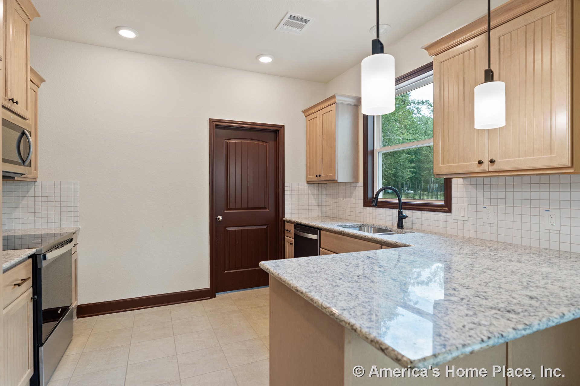 Granite countertops with light wood cabinetry, tile backsplash, pendant lighting, double sink beneath window, brown paneled door, built-in microwave and dishwasher, tile flooring.