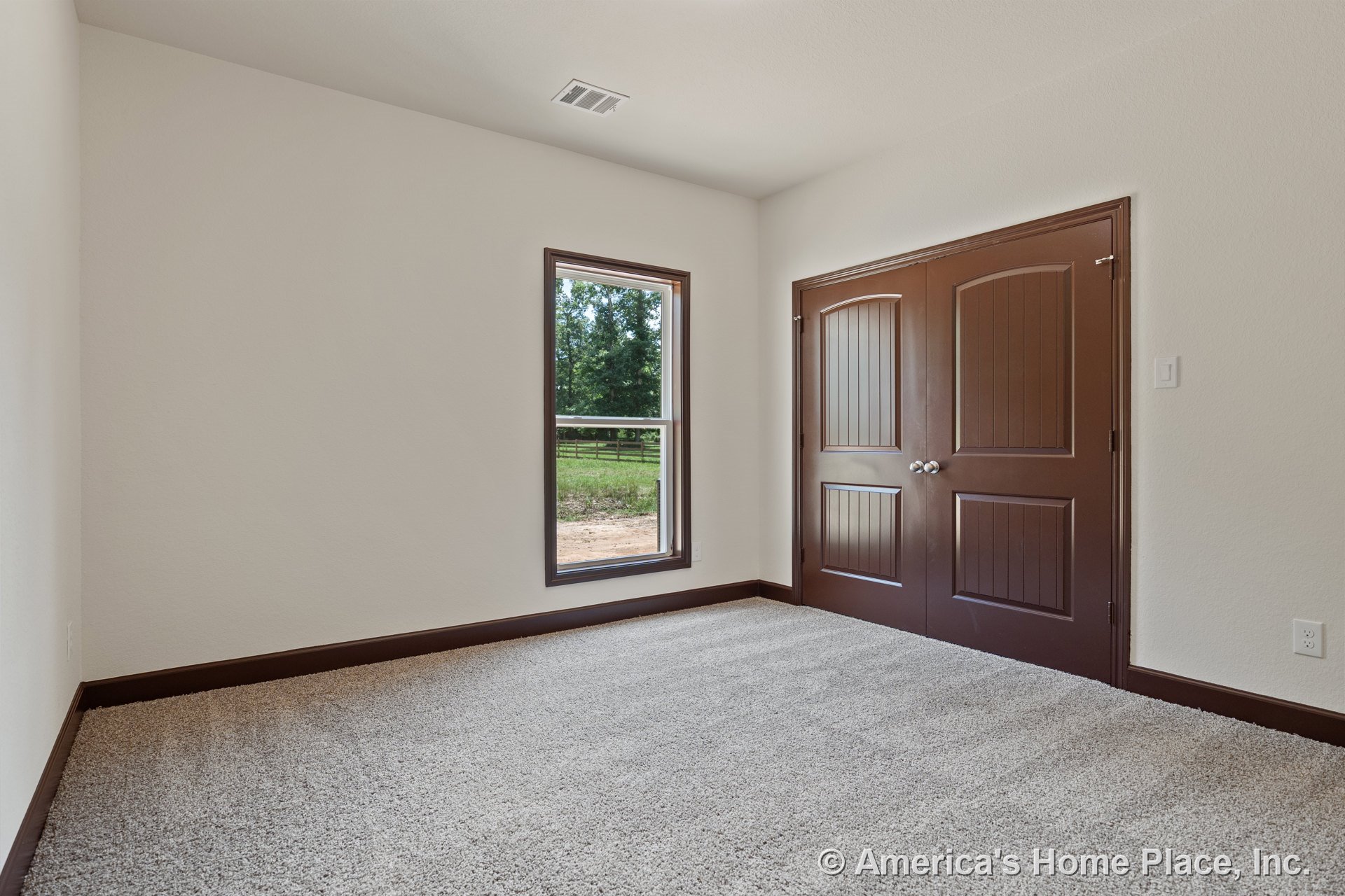 Bedroom with carpet flooring, brown baseboards, white walls, double closet doors with door hardware, single window allowing natural light, and vented ceiling.