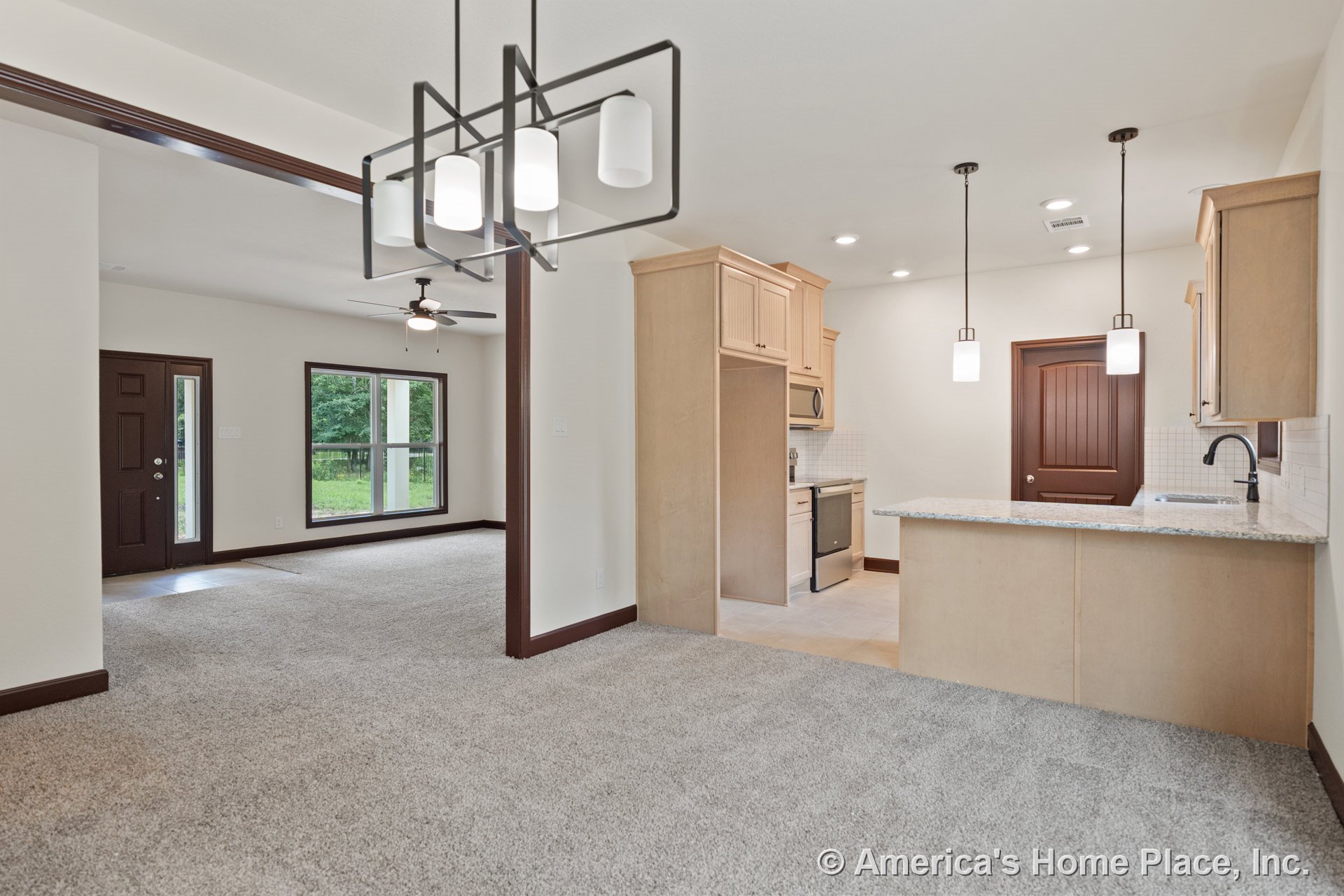 Open floor plan with carpeted living area, large windows framed in dark trim, kitchen featuring light wood cabinets, granite countertops, pendant and recessed lighting, and dark