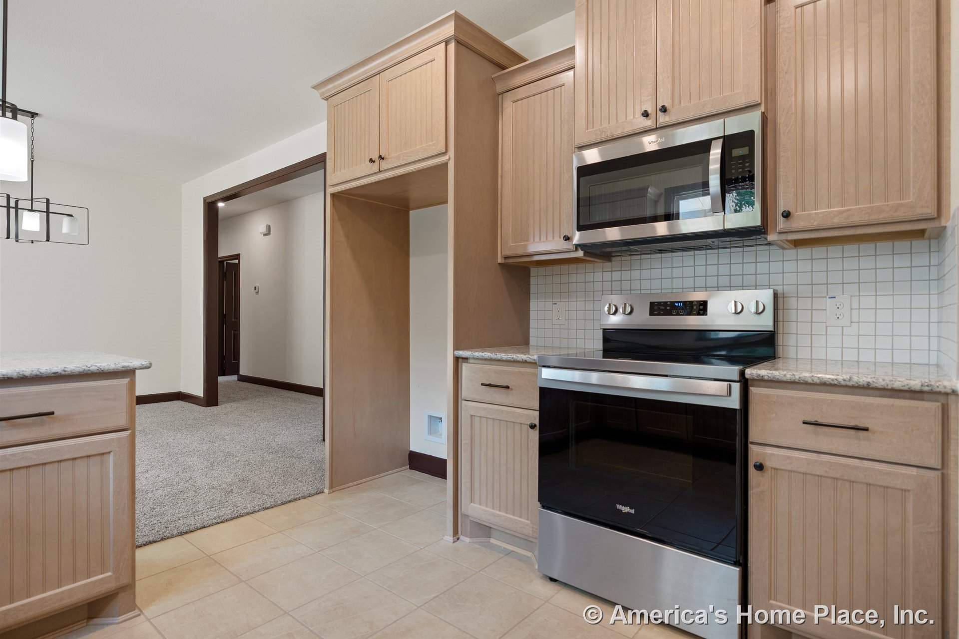 Light wood kitchen cabinets with granite countertops, stainless steel oven and built-in microwave, tile backsplash, and tile flooring.