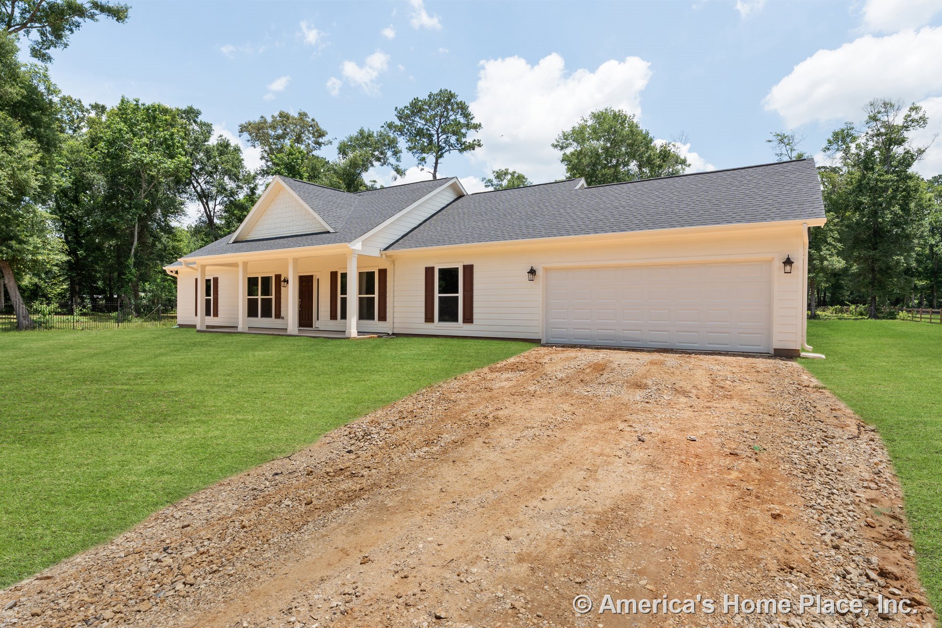 Covered front porch with white columns, double garage doors, white horizontal siding, brown window shutters, gable roof with shingles, exterior wall lanterns, paved driveway, and