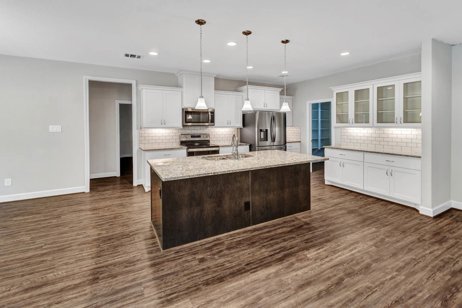 Kitchen with wood flooring, white cabinets with glass doors, wooden countertop, stainless steel refrigerator, sink beneath a window