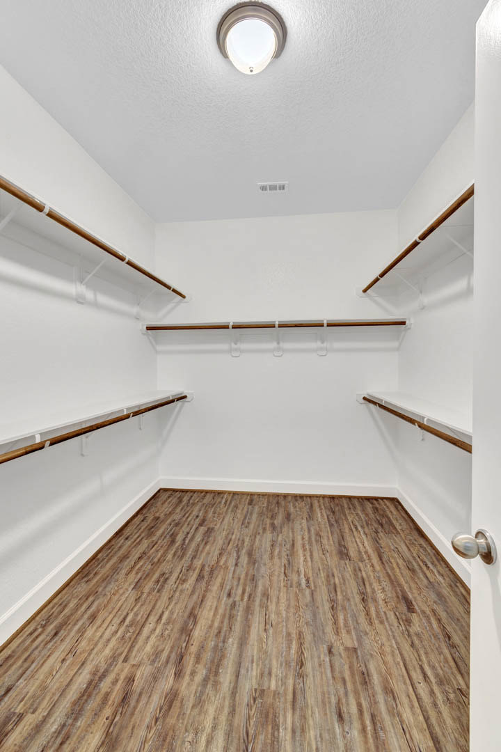 Empty closet with hardwood floor, white walls, and built-in wooden shelves