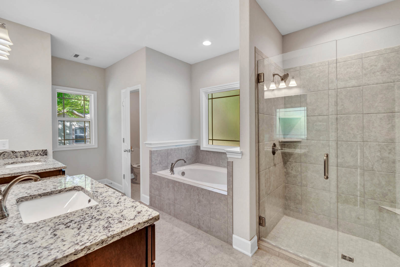 Modern bathroom featuring a freestanding bathtub, white sink with black speckled marble countertop, large window overlooking trees, and minimalist fixtures.