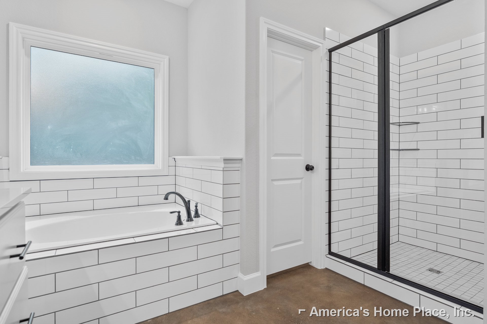 White bathtub with tile surround, glass shower door, frosted window, black faucet on white sink, metal towel bar, light-colored floor tiles