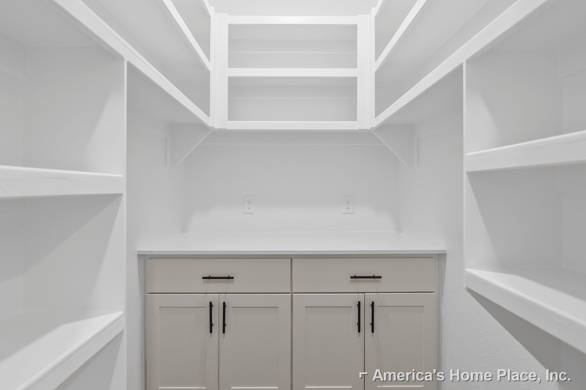 White closet with built-in shelves, white cabinetry featuring black handles, smooth white surfaces, and plaster walls in a modern indoor space.