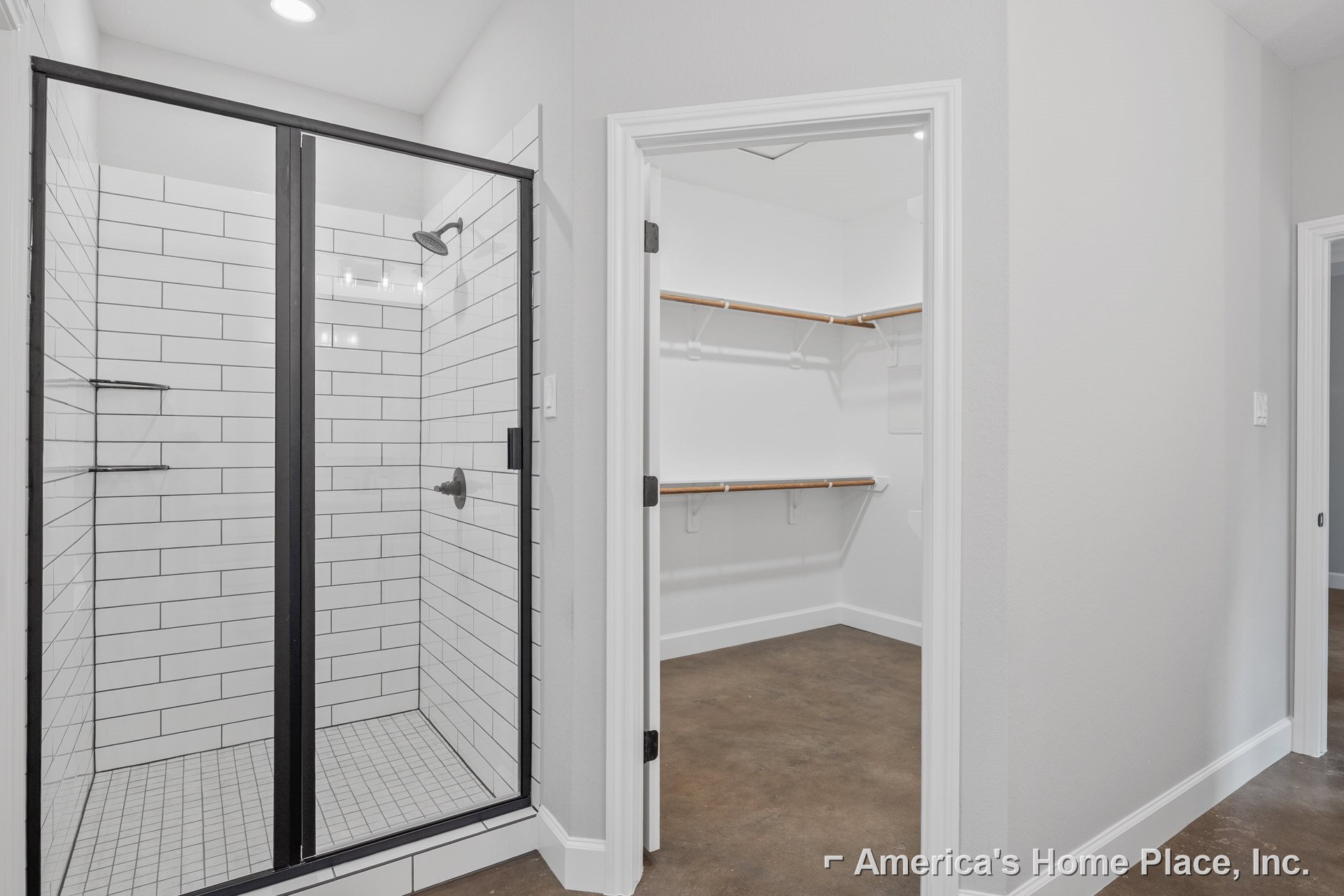 Bathroom featuring a walk-in shower with glass enclosure, modern tile flooring, and an adjacent walk-in closet with wooden hanging rail and open door leading to another room