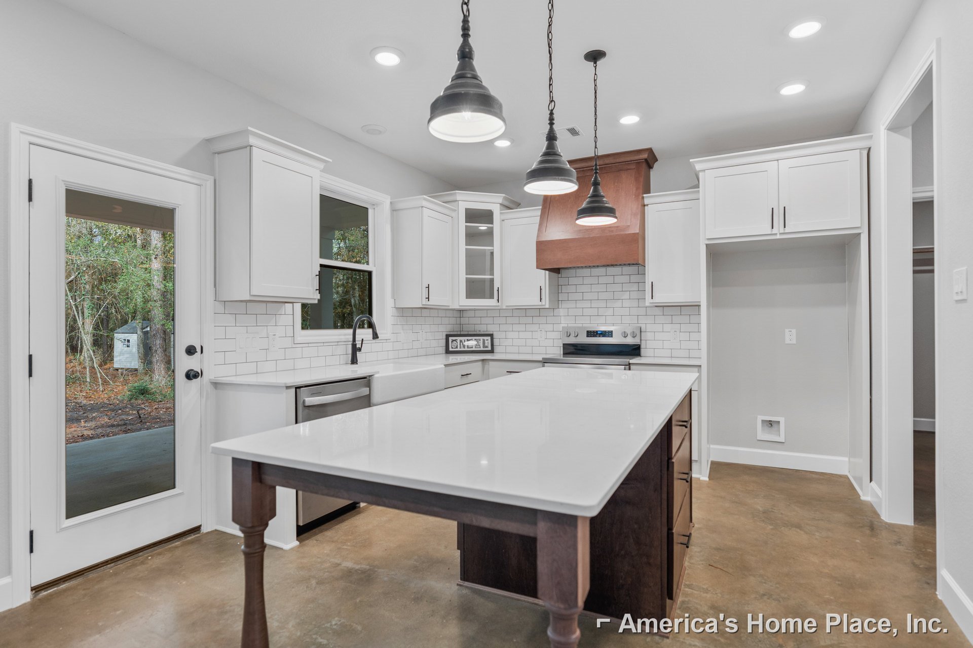 White kitchen featuring shaker cabinets, quartz countertops, spacious central island with built-in sink, pendant lighting, and white tile flooring.