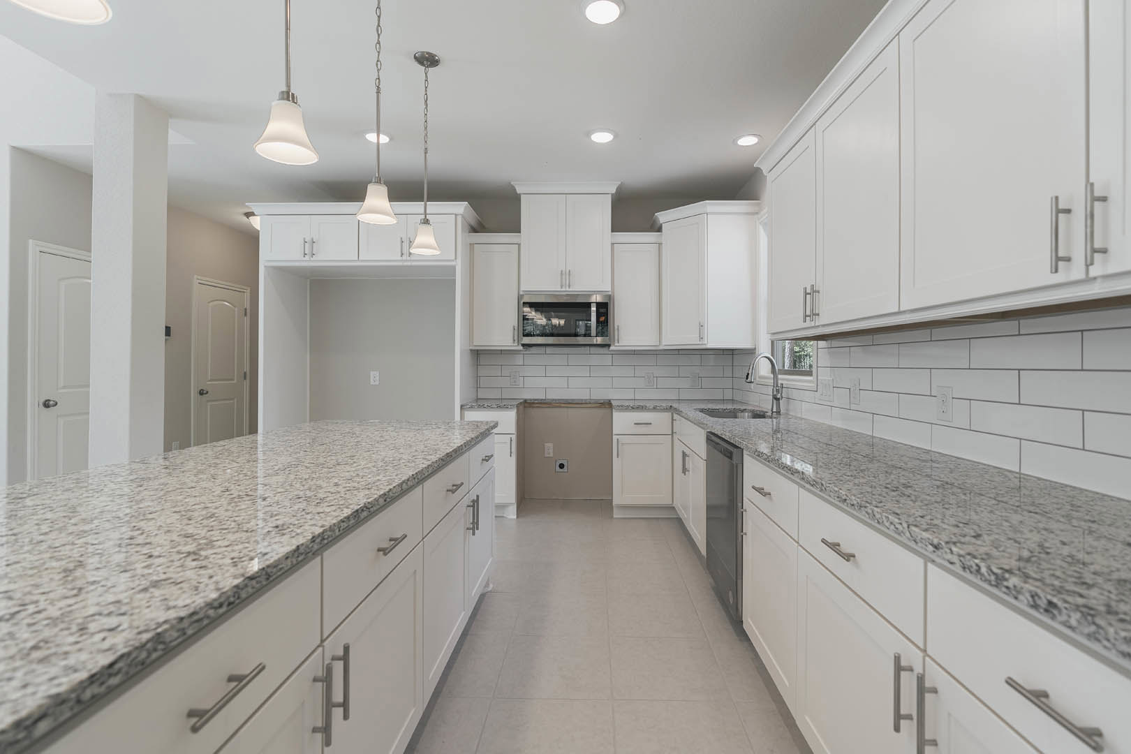 White kitchen with granite countertops, stainless steel appliances, tile backsplash, and recessed lighting