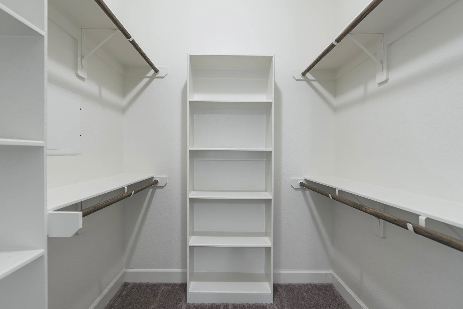 White built-in shelving unit with two shelves against a white plaster wall, black border trim, and adjacent wooden pole with white plastic clips.