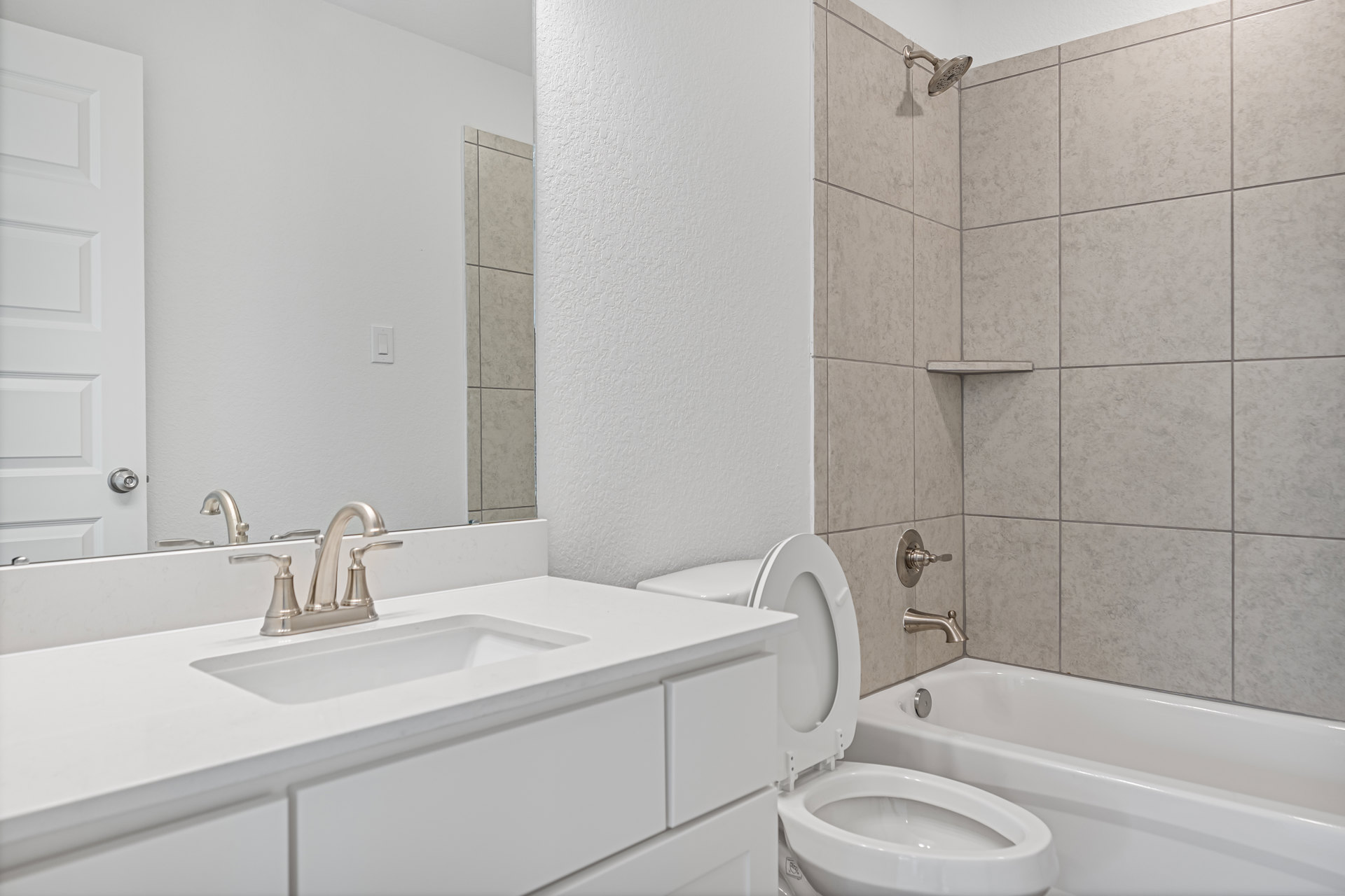White tile bathroom featuring a white toilet with closed seat, pedestal sink with chrome faucet, white bathtub, and paneled door.