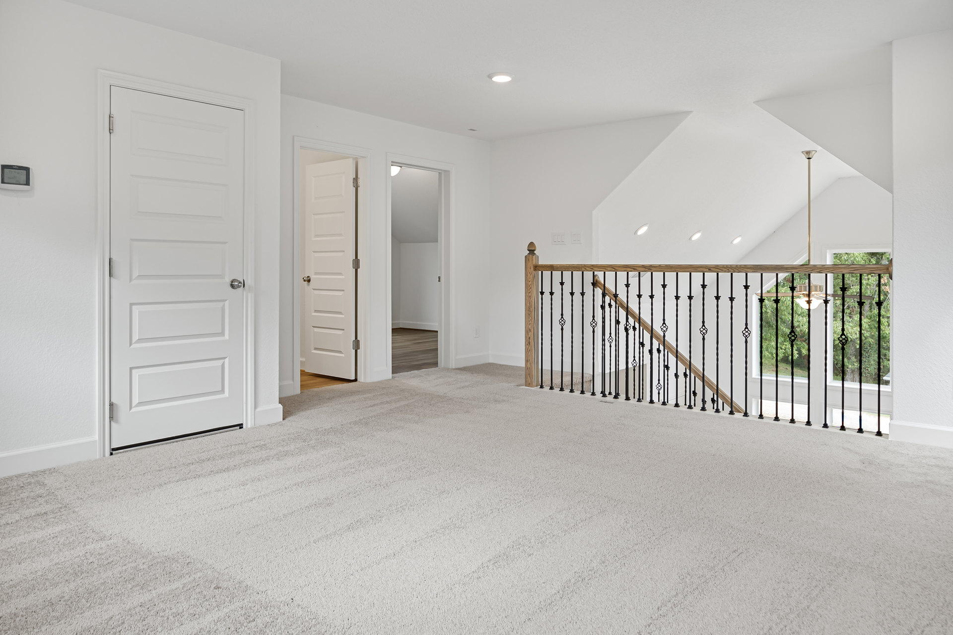 White-walled room featuring a white carpeted staircase with black railing, adjacent to a white door with a silver knob, door partially open.