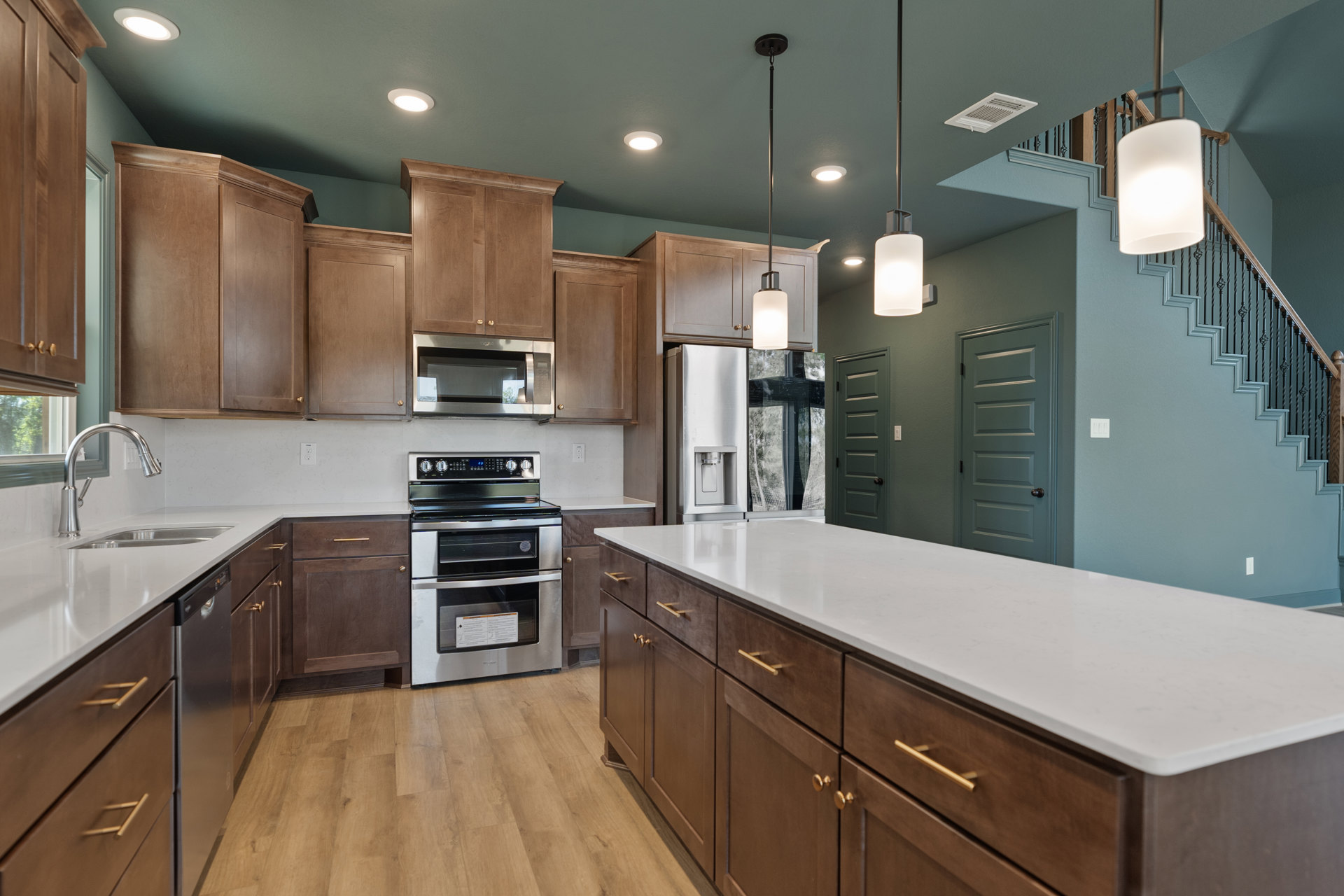 Kitchen featuring wood cabinetry, white countertops, stainless steel stove with glass door, built-in microwave, white lamp shade, and brown lower cabinets
