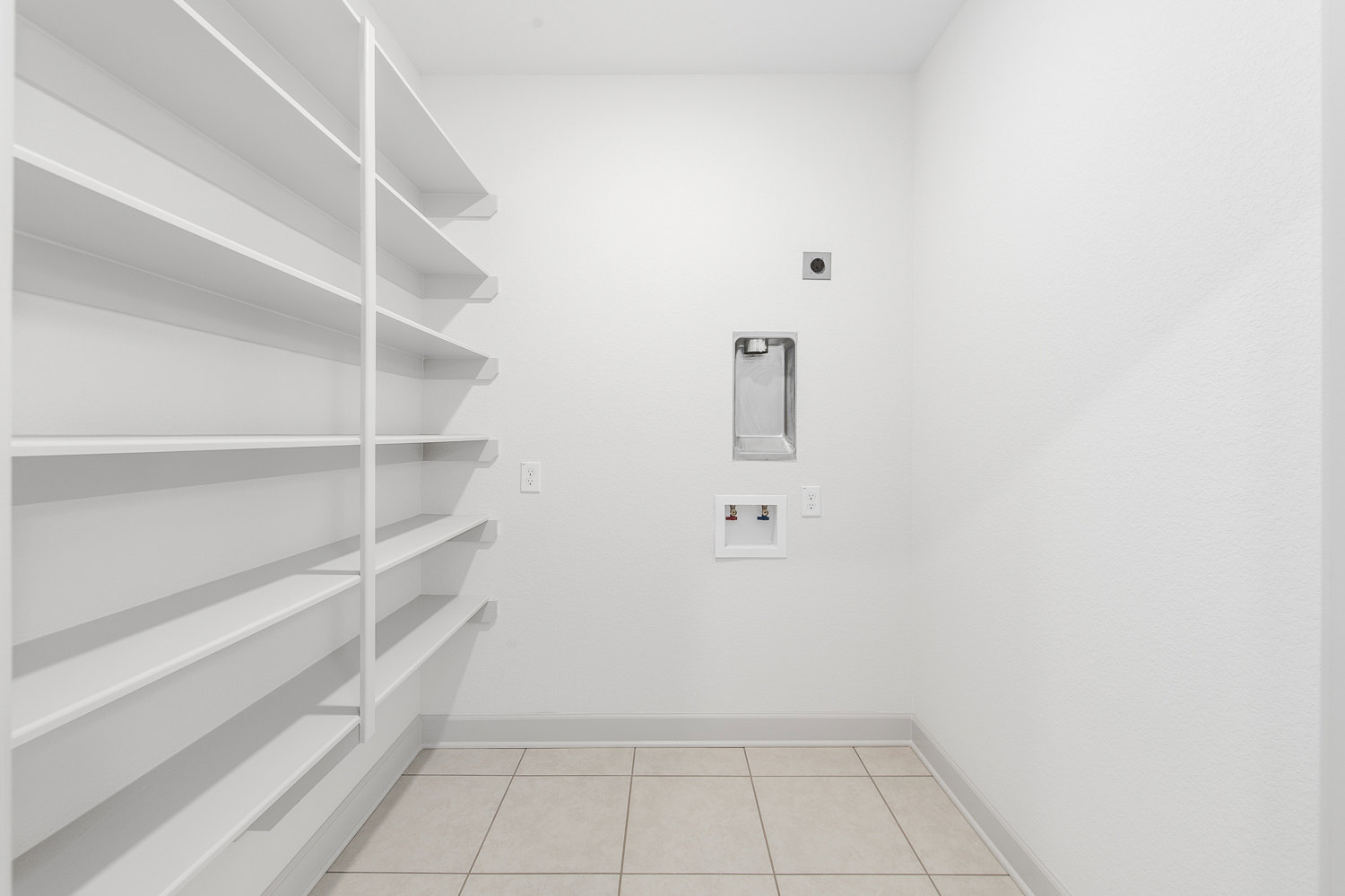 Built-in white shelves against a plaster wall in a bright room with tile flooring and a white ceiling