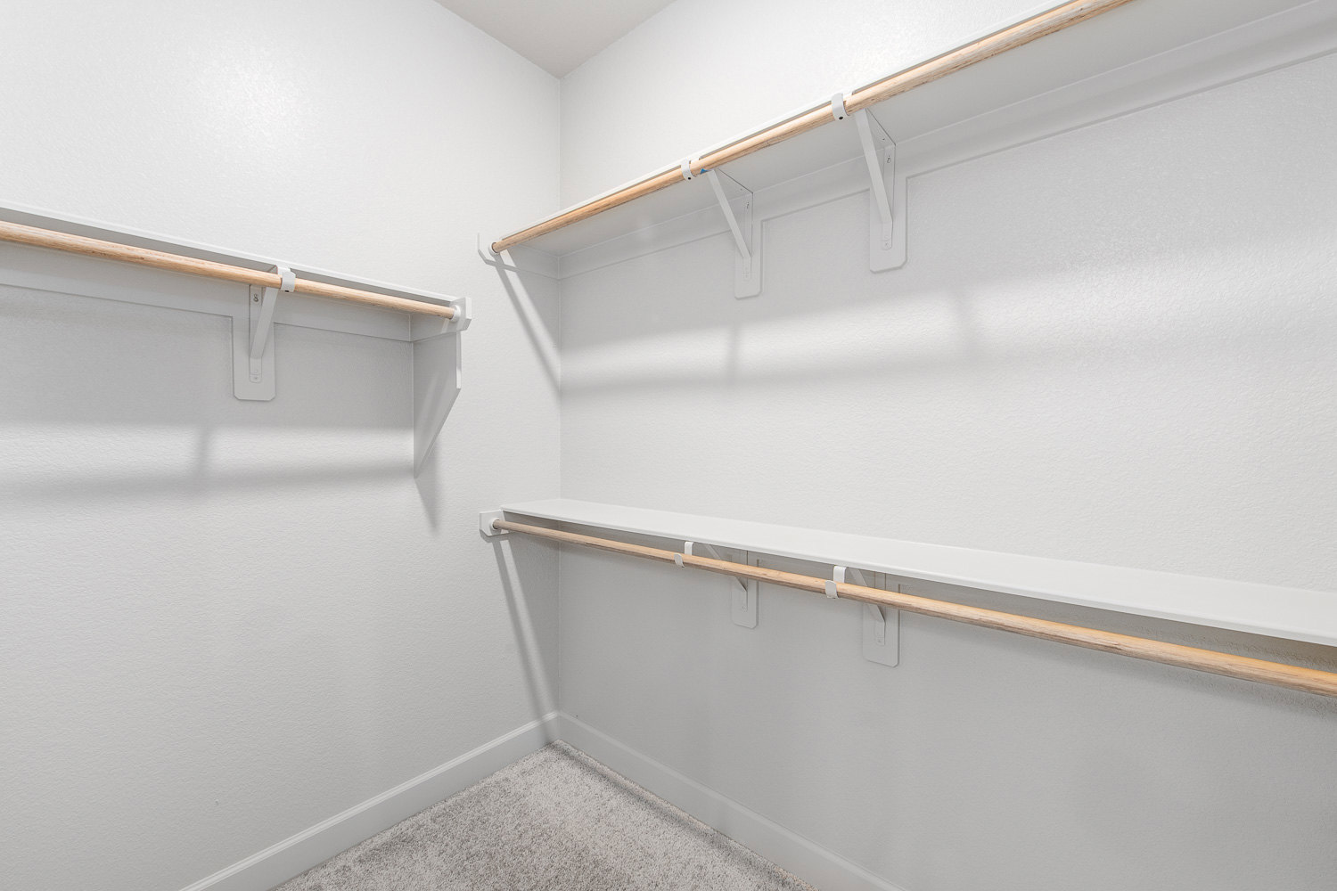 White closet with built-in wooden shelves and carpeted floor