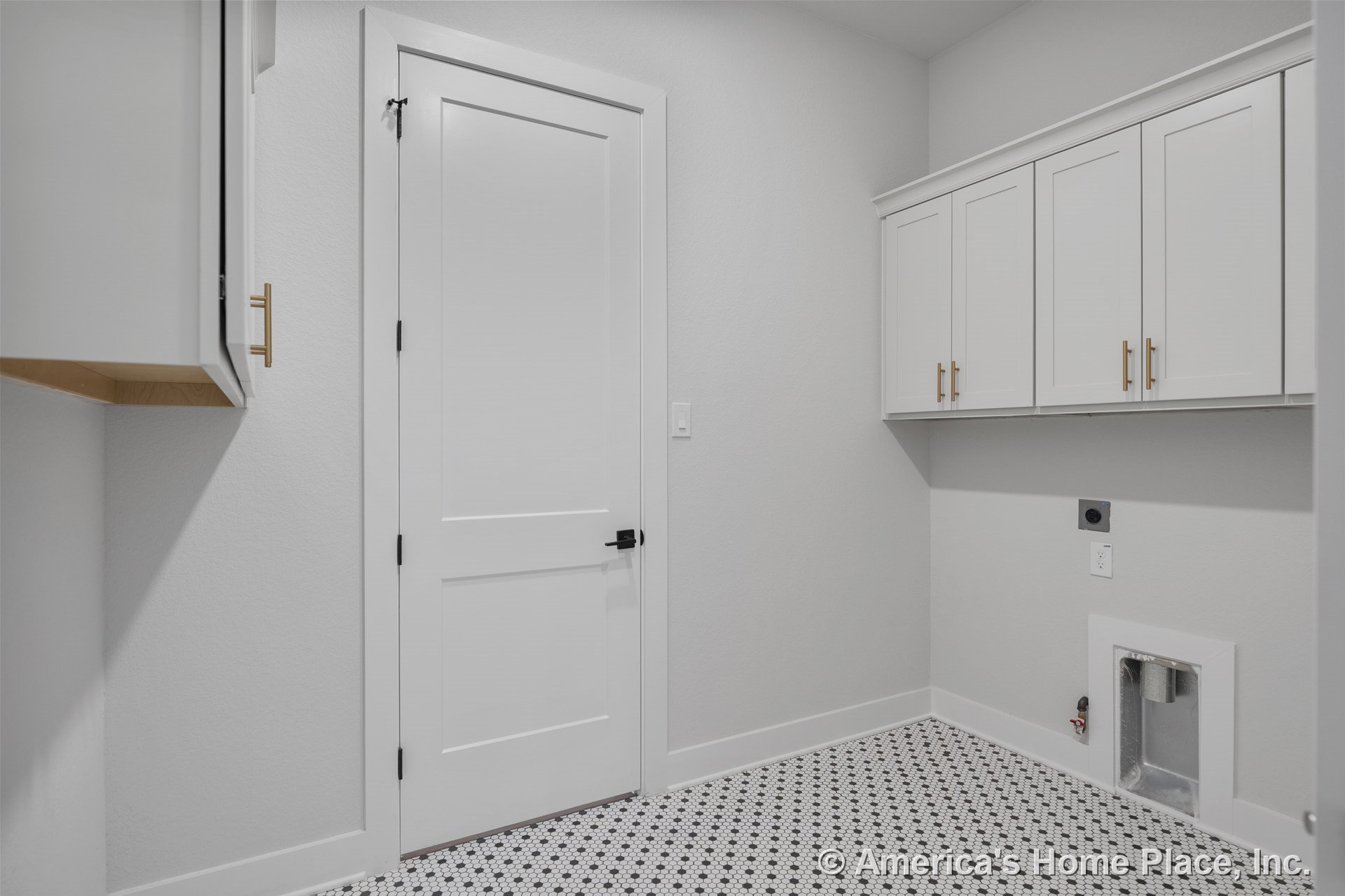 White shaker cabinets with brass hardware, wall-mounted upper cabinetry, patterned hex tile flooring, laundry hookups, white trim and interior door, neutral wall color, modern