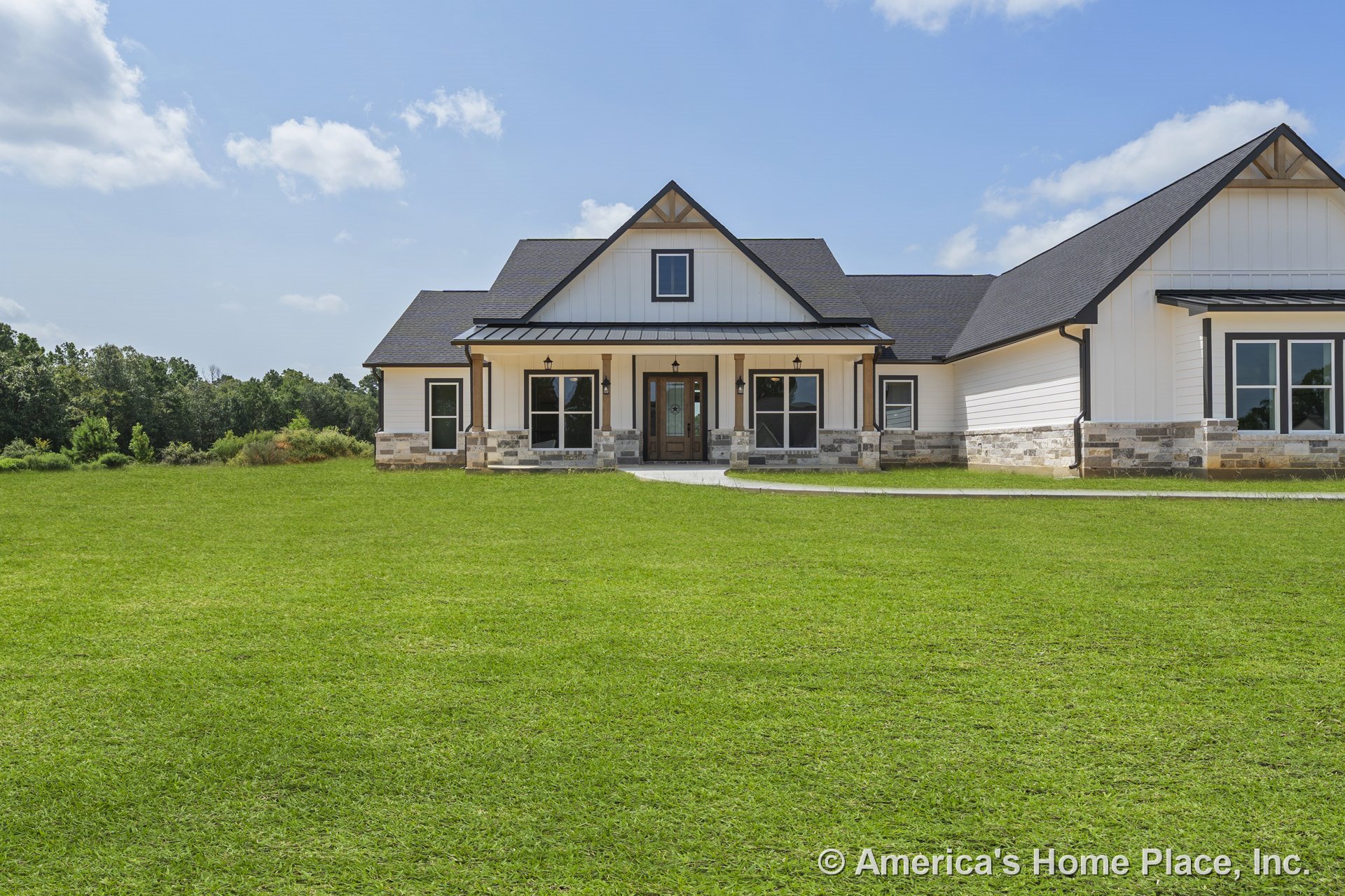 Modern farmhouse exterior with white board and batten siding, stone foundation accents, covered front porch supported by columns, multiple windows with dark trim, dark roof