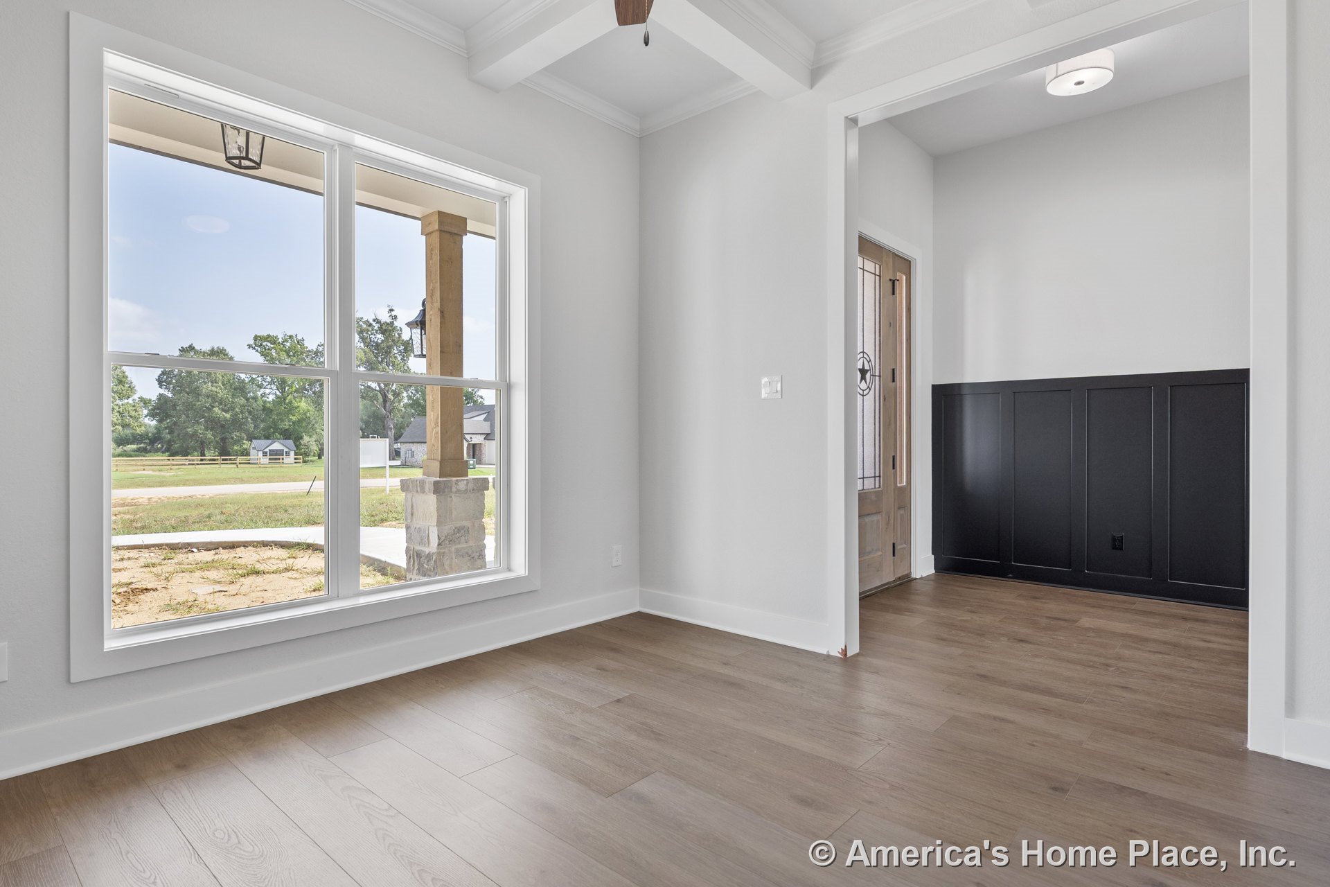 Wide plank wood flooring and black wainscoting in foyer with large double window, white trim, wood front door with glass panels, tray ceiling featuring ceiling fan, and abundant