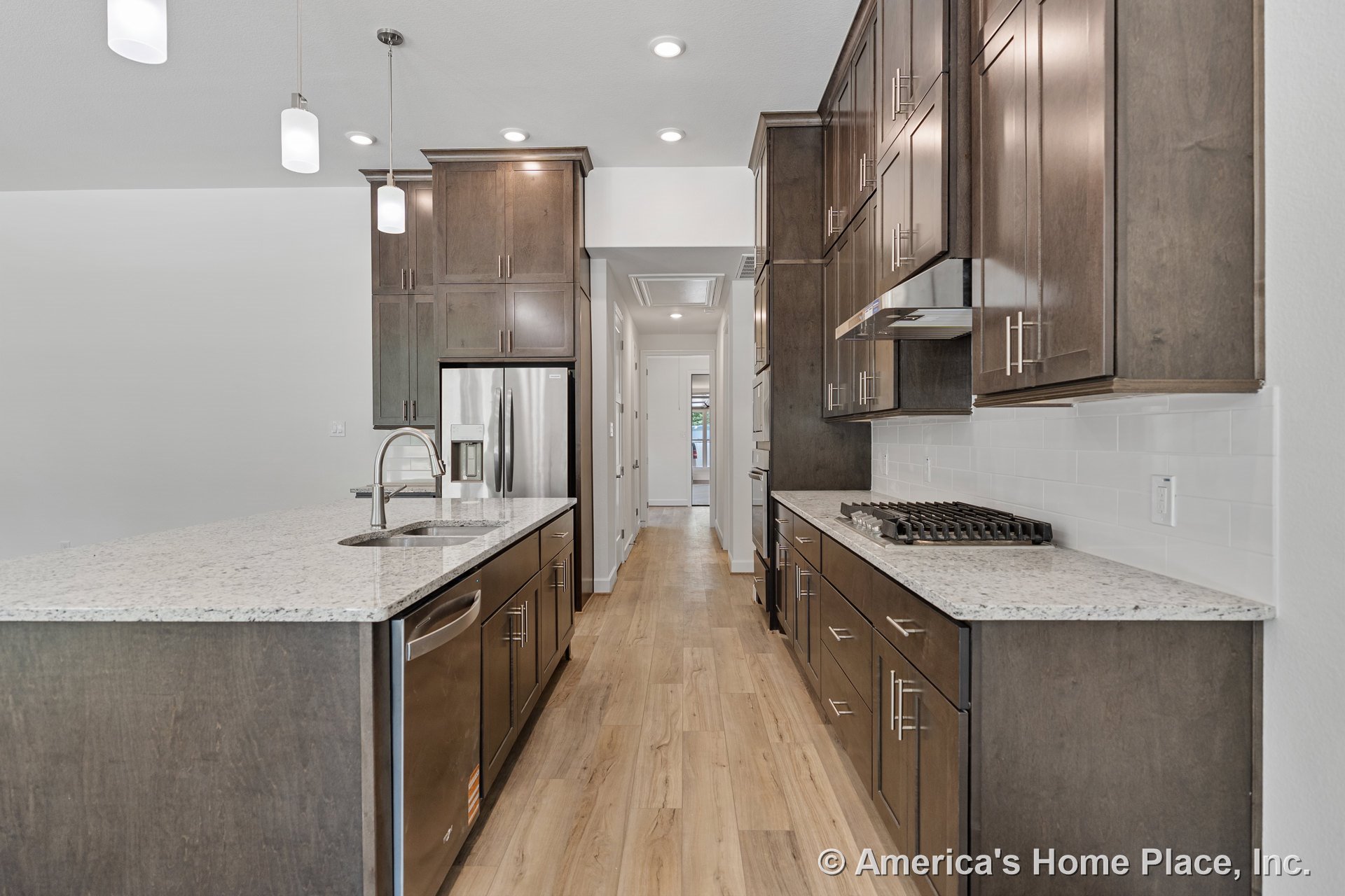 Dark wood kitchen cabinets with granite countertops, stainless steel appliances, gas cooktop and hood, double bowl undermount sink, subway tile backsplash, pendant and recessed