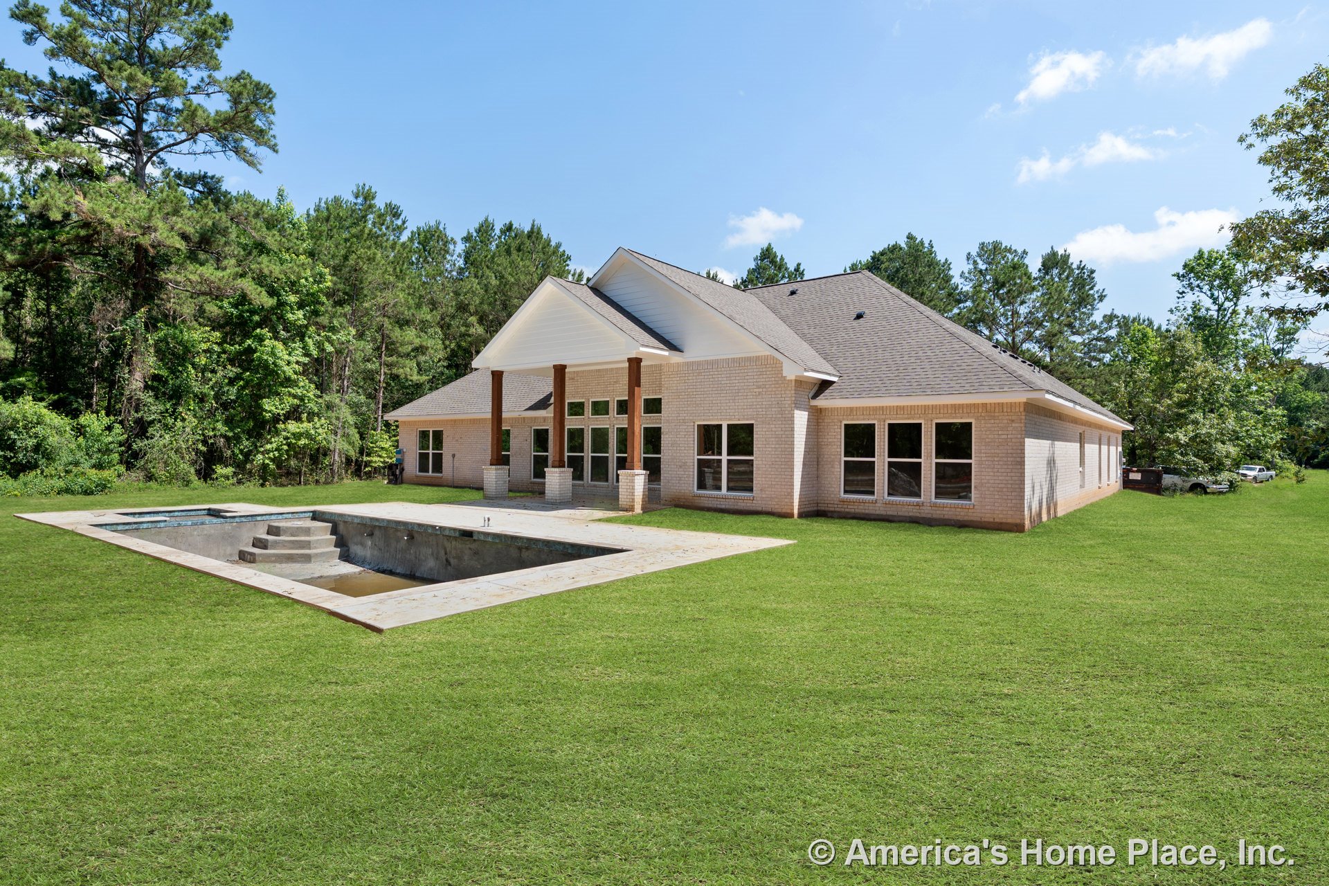 Light brick exterior with hip shingle roof, covered patio supported by wood columns, multiple large windows, unfinished in-ground pool with concrete surround, landscaped yard.