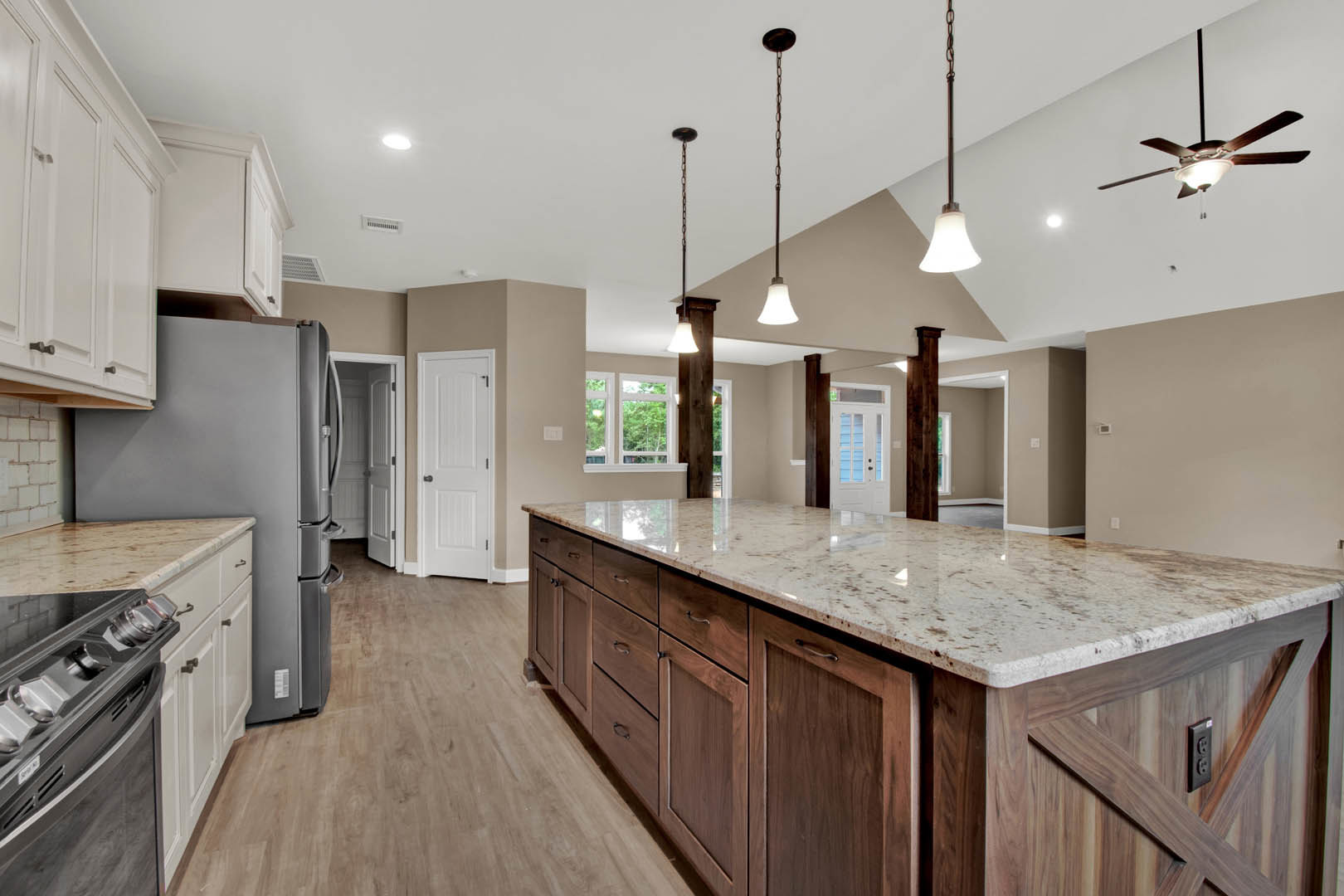 Kitchen with marble island countertop, white cabinets, stainless steel stovetop, ceiling fan with light, and white door featuring black handle