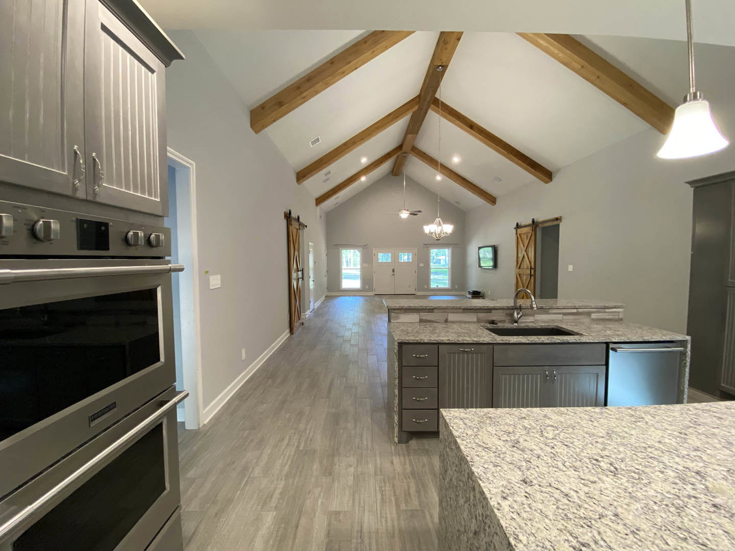 Open-concept kitchen and dining area with white cabinetry, stainless steel appliances, quartz countertop, modern pendant lighting, and brushed metal faucet