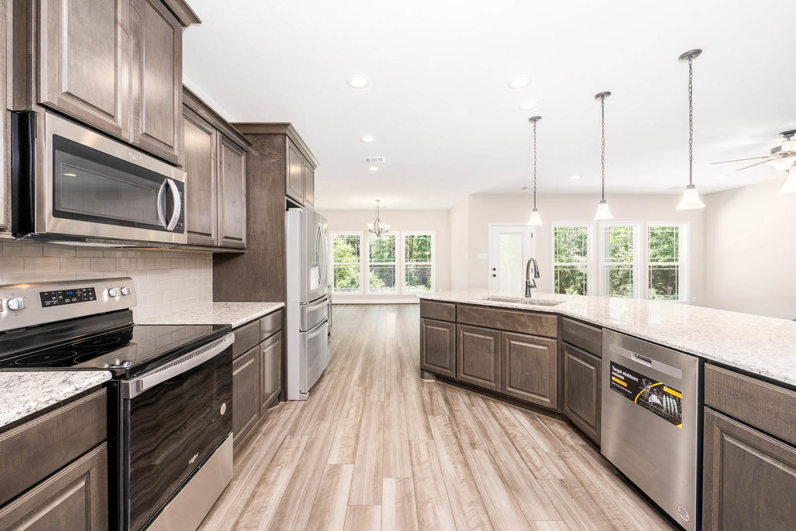 Kitchen with natural wood flooring, stainless steel refrigerator, stove, and microwave, white cabinetry, stone countertops, and modern fixtures