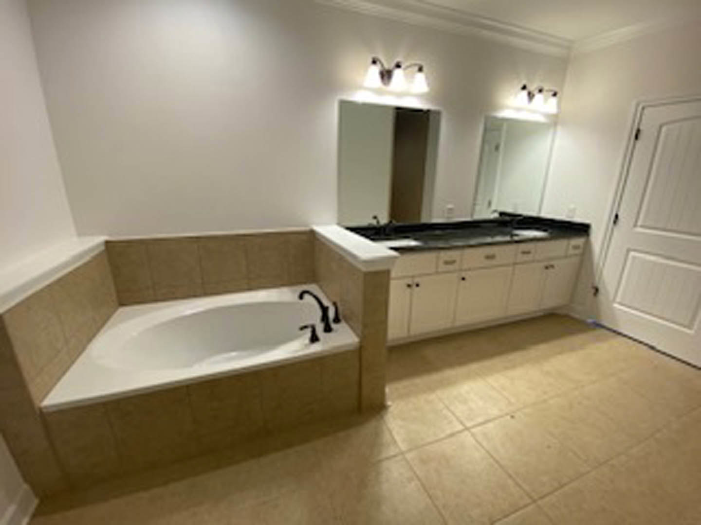 White freestanding bathtub beside a modern vanity with vessel sink, gray tile flooring, and light-colored walls