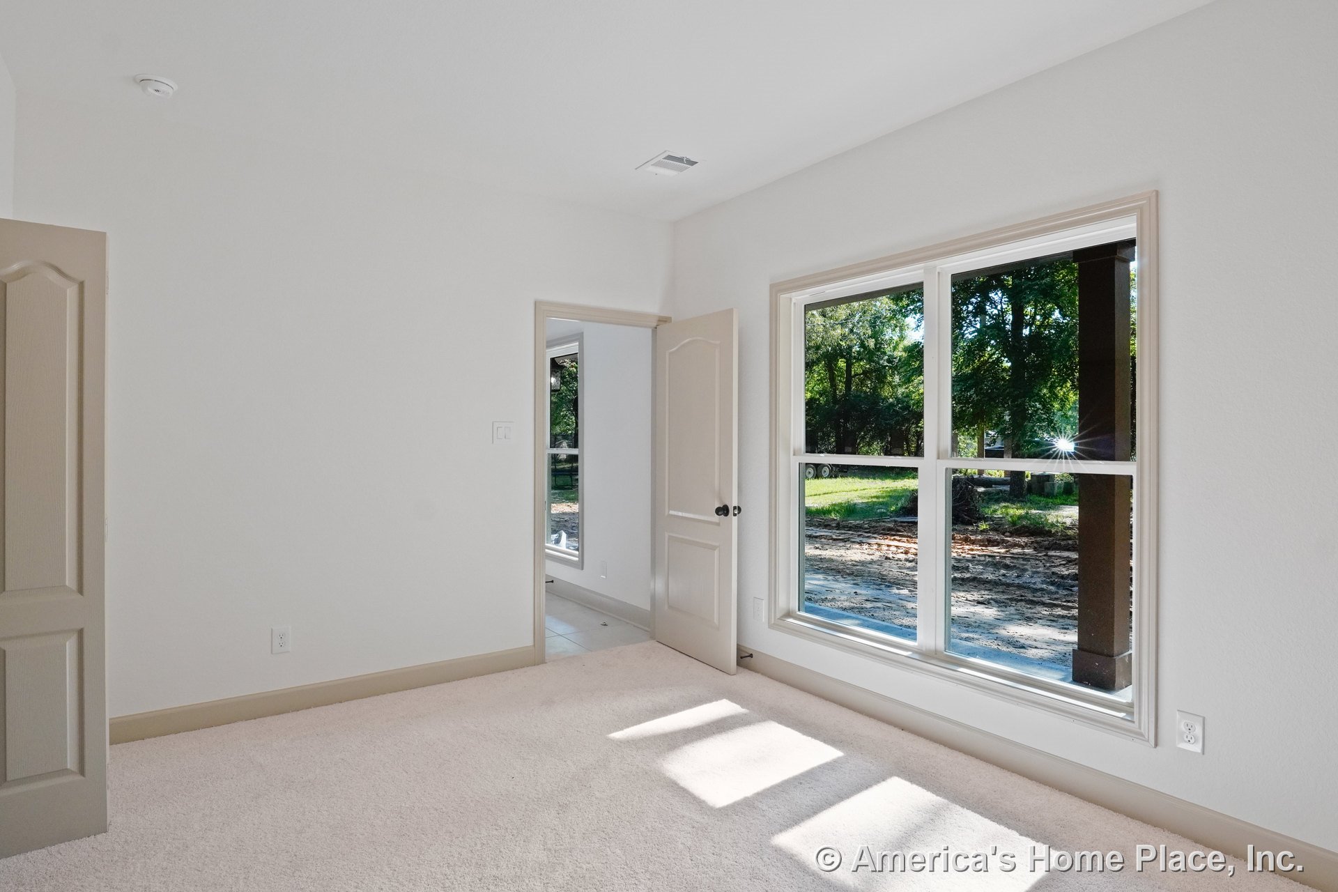 Bedroom with large double-pane windows, beige carpet flooring, neutral wall color, beige door and trim, baseboard molding, and ceiling vent.