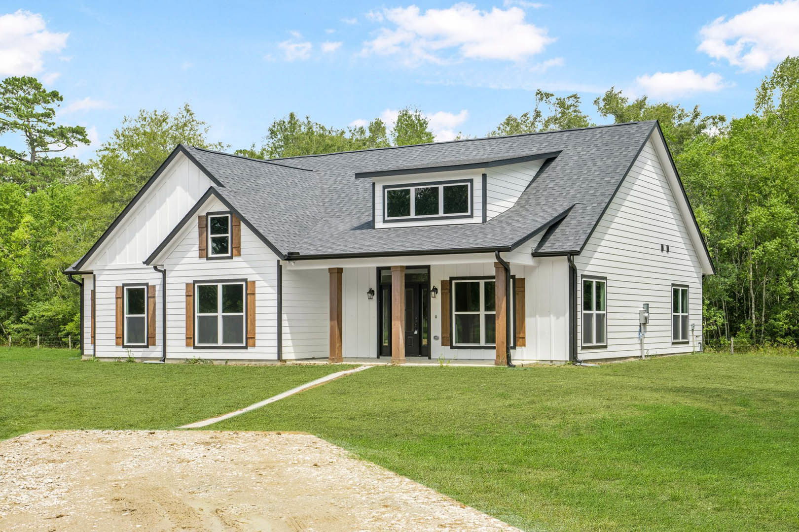White clapboard house with covered porch, white-framed windows, green lawn, stone path, blue sky, and Robert Frost Farm visible in the background.