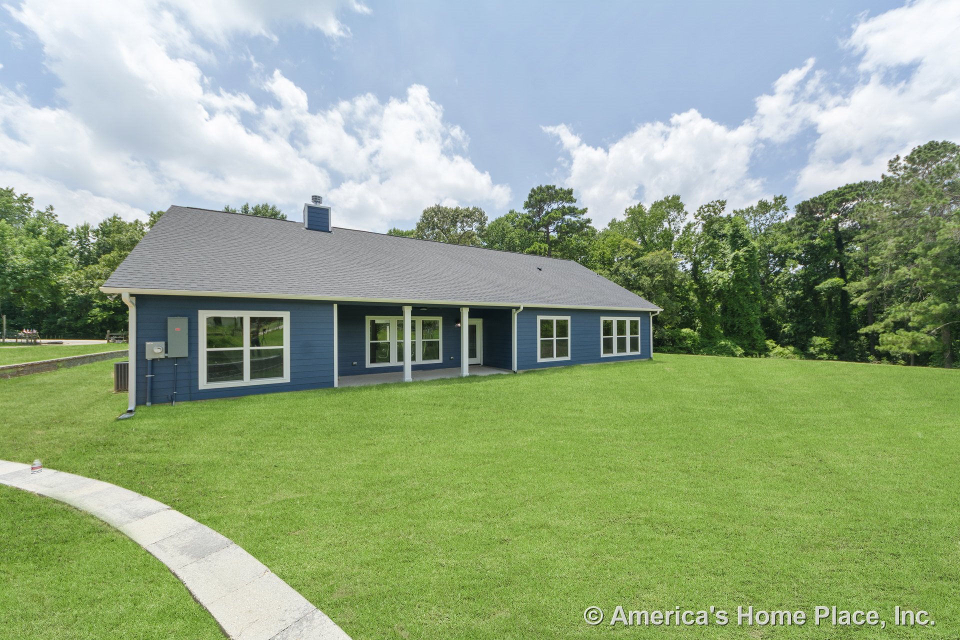 Covered rear porch with white columns, blue horizontal siding, multiple large windows, gray shingle roof, white trim, and spacious backyard.